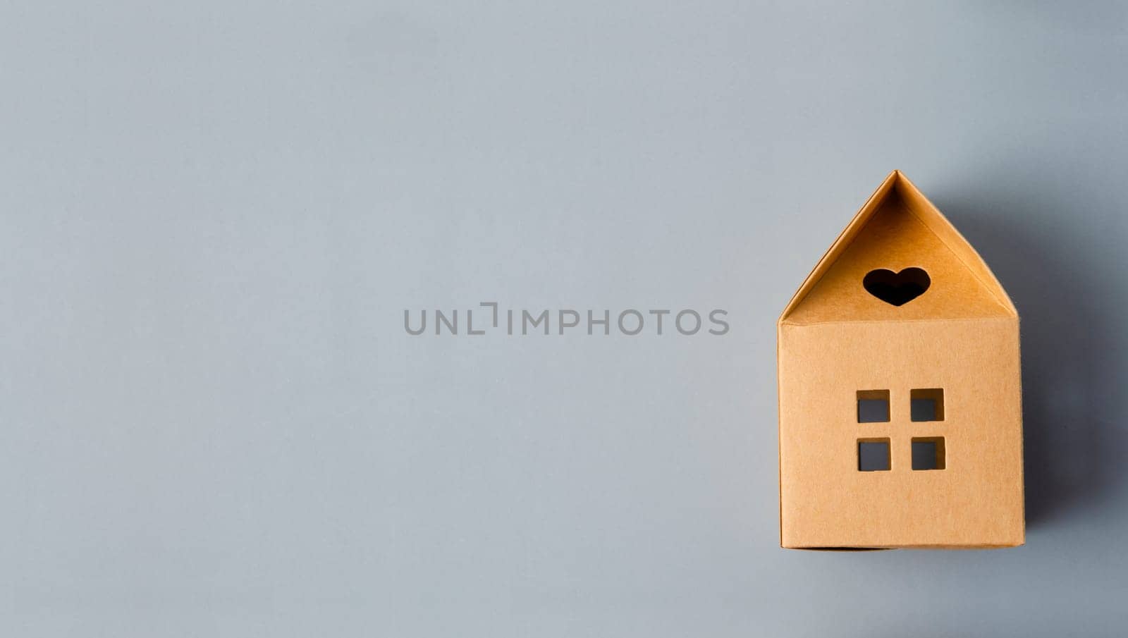 Brown paper house origami on gray color background with empty space for your text or message.