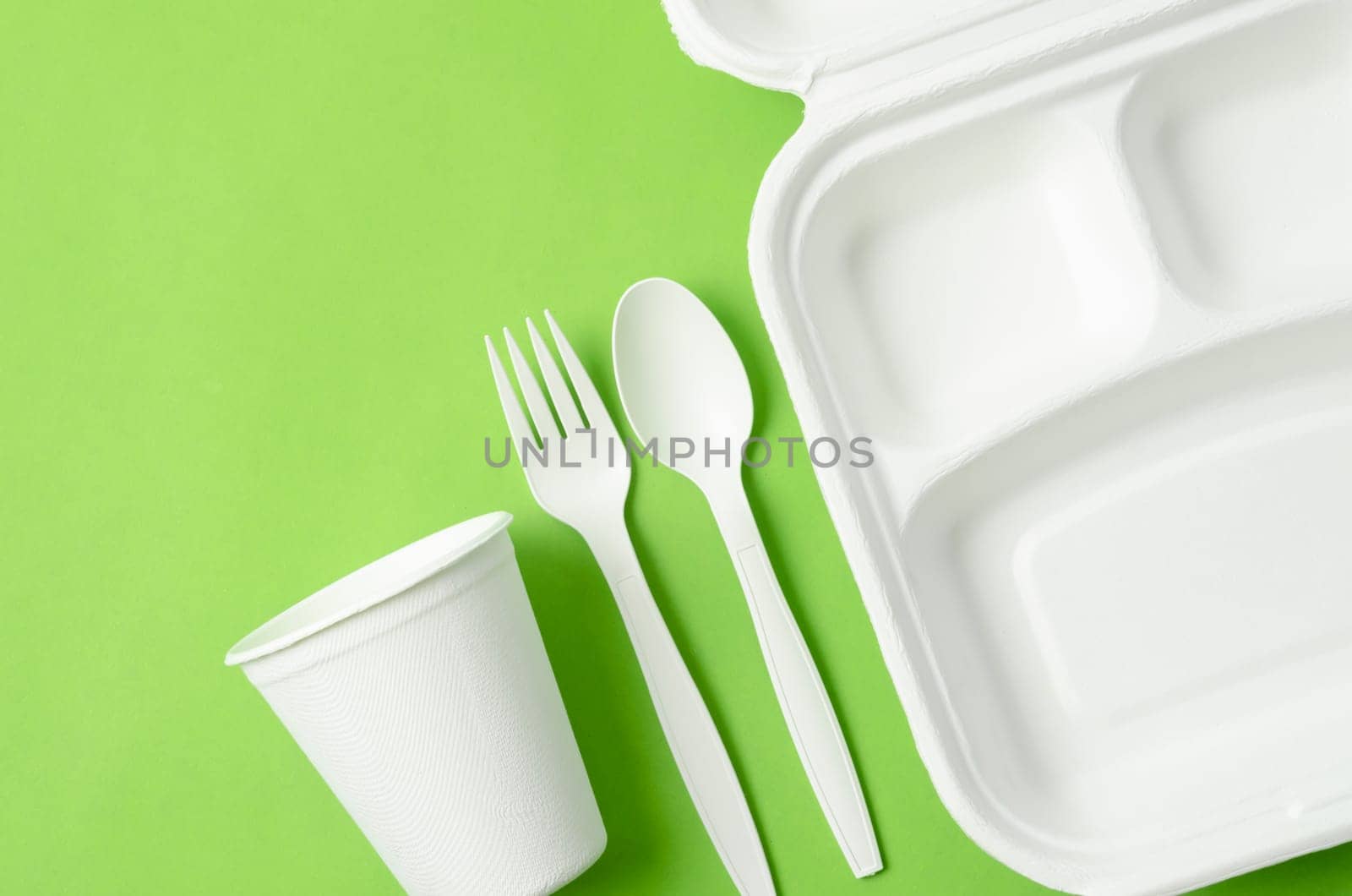 Eco friendly biodegradable paper disposable for packaging food and paper glass on green background.