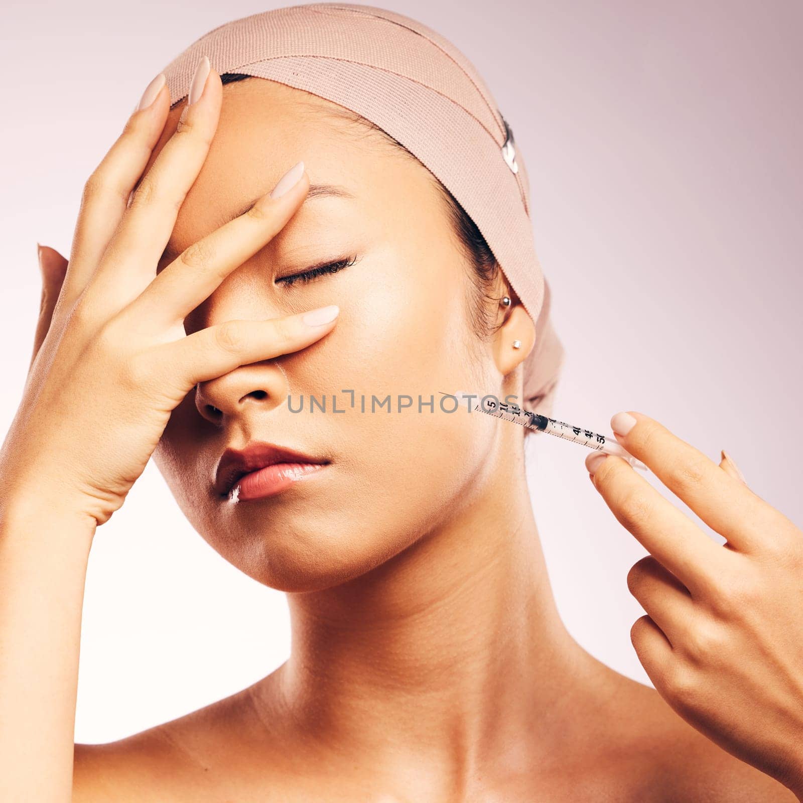 Woman, plastic surgery and syringe in studio background with bandage for skincare of asian model. Female person, injection and touch face with collagen, cosmetic treatment and beauty of wellness