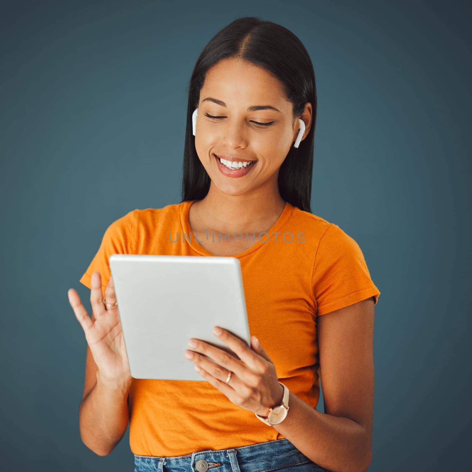 Woman, tablet and listening to music online while streaming and happy on a studio background. Smile of a young gen z person with mobile app for podcast, radio or audio with network internet to relax by YuriArcurs