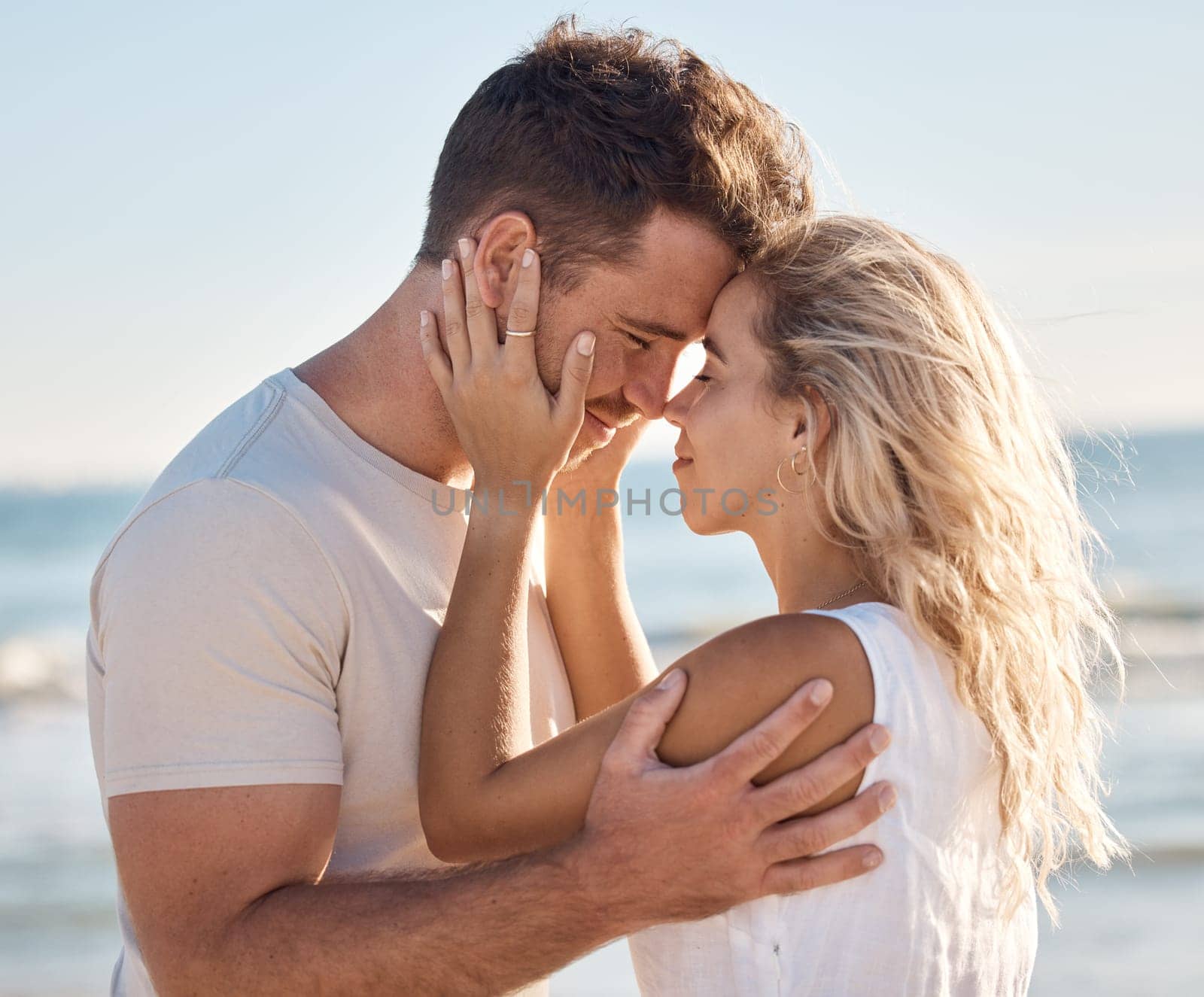 Love, beach and couple with head together for intimacy, romance and joy on weekend. Relationship, happiness and young man and woman by ocean enjoying summer holiday, vacation and honeymoon in nature.