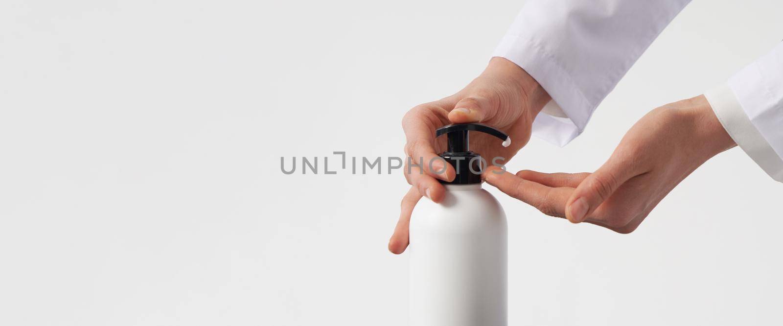 Woman hands pushing pump plastic soap bottle on white background