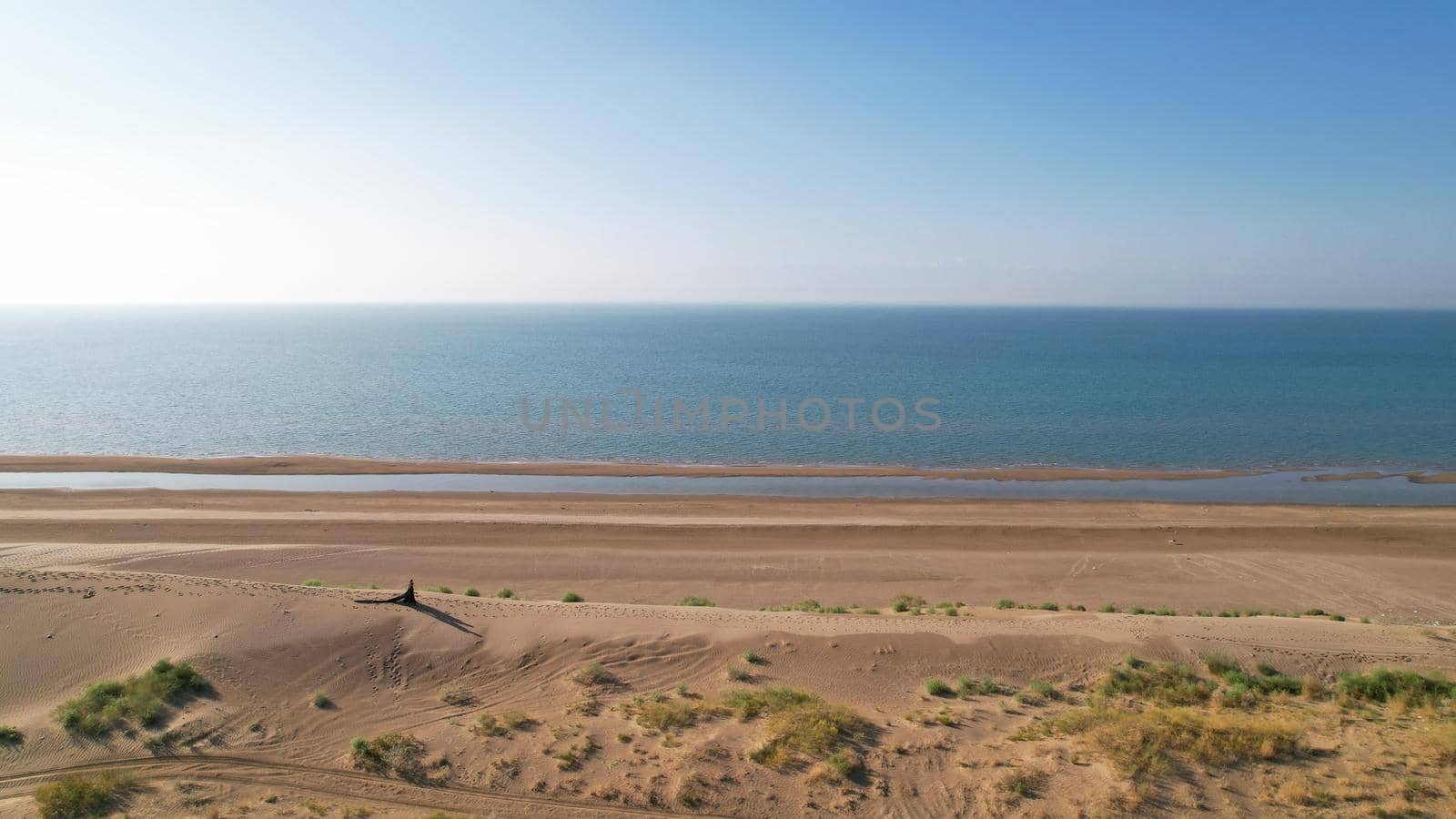 A young couple walk along a sand dune near the sea by Passcal