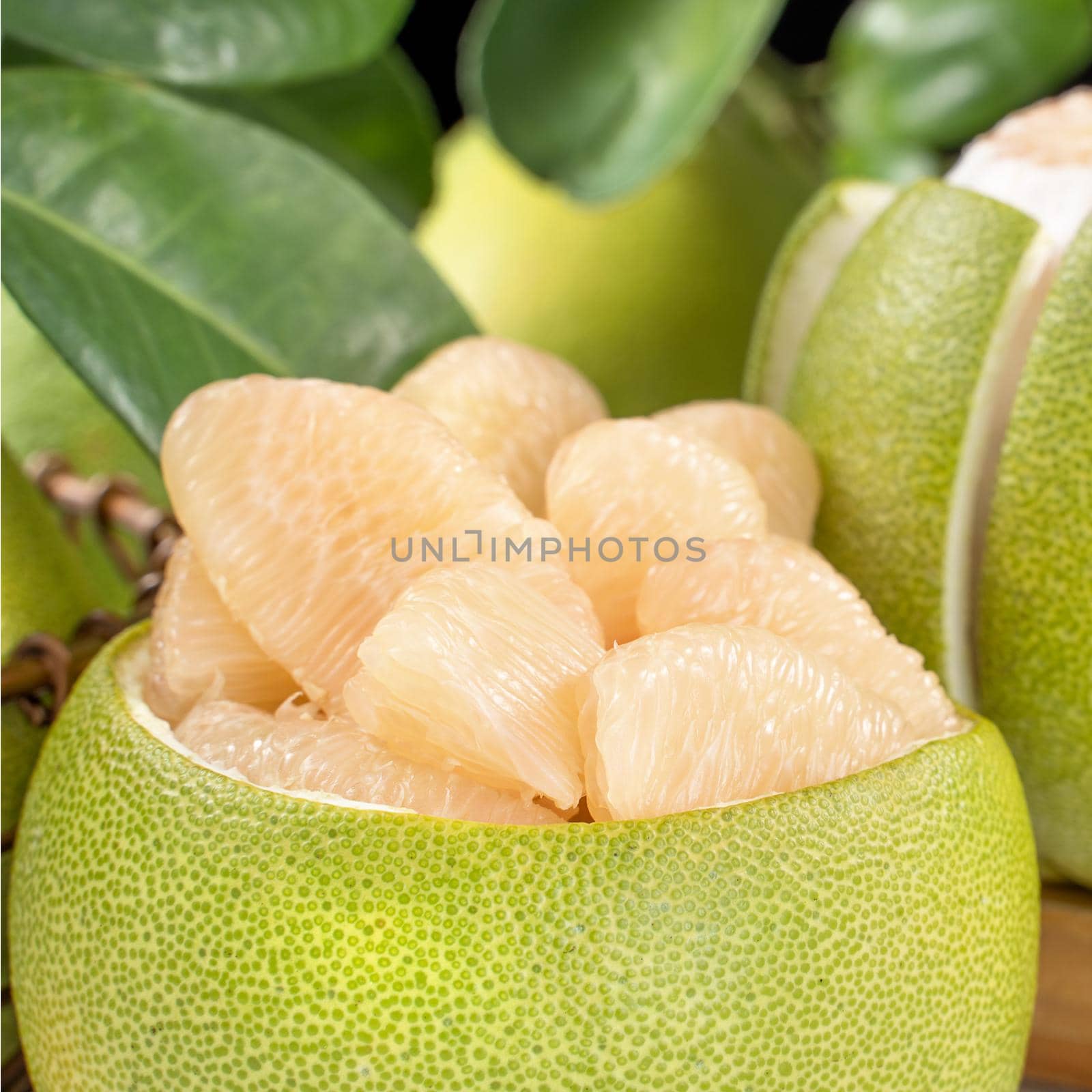 Fresh peeled pomelo, grapefruit, shaddock with green leaf on bright wooden plank table. Seasonal fruit near mid-autumn festival, close up, copy space