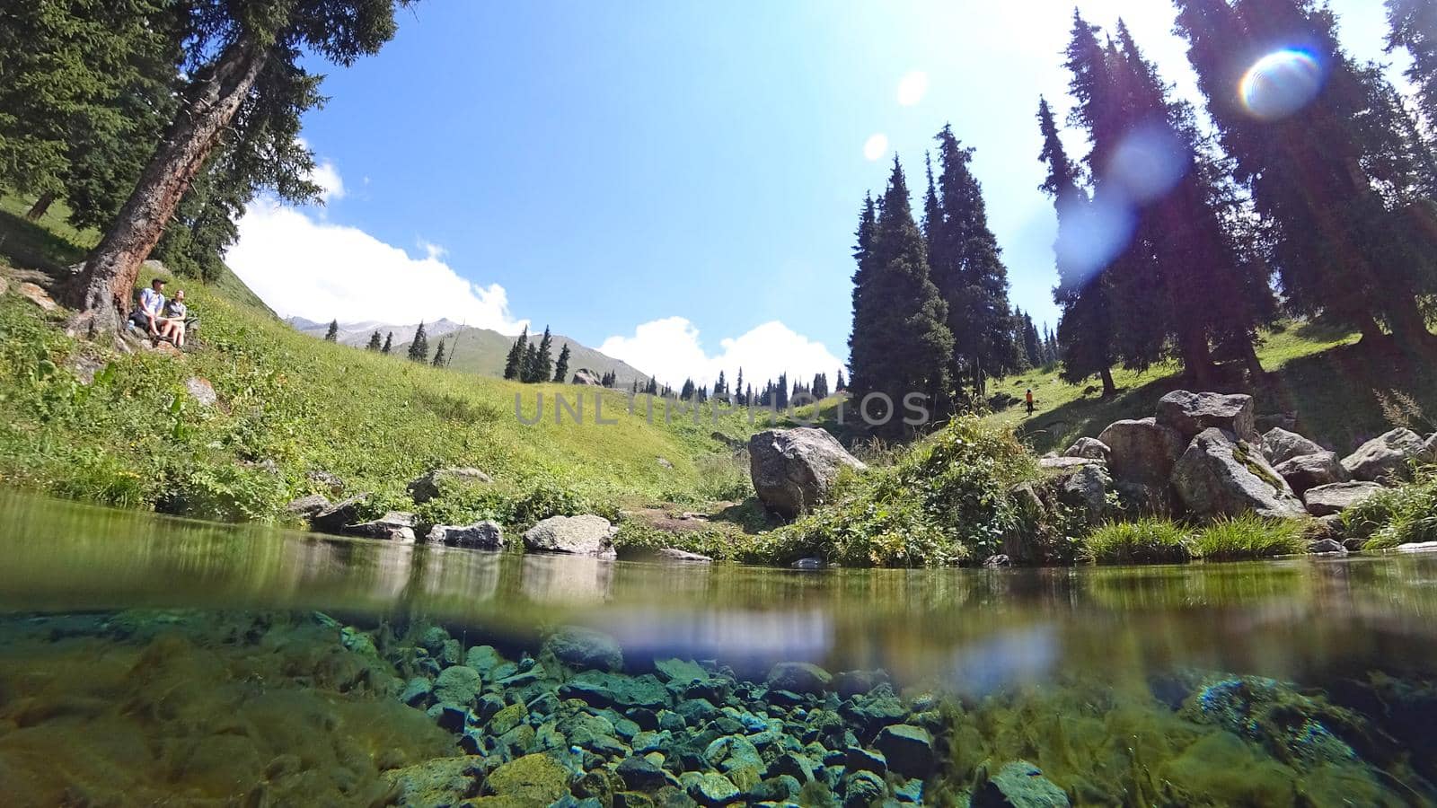 An incredible underwater world of a mountain river. Crystal clear clear water. Yellow rocks and green-brown algae. The rays of light are refracted into a blue color in the distance. An unusual world