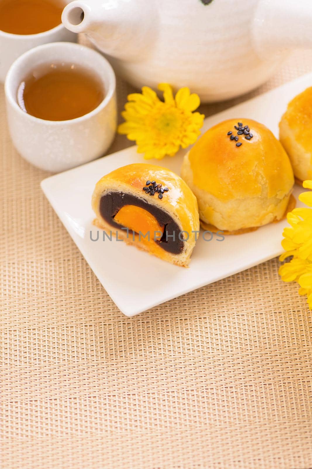 Tasty baked egg yolk pastry moon cake for Mid-Autumn Festival on bright wooden table background. Chinese festive food concept, close up, copy space.