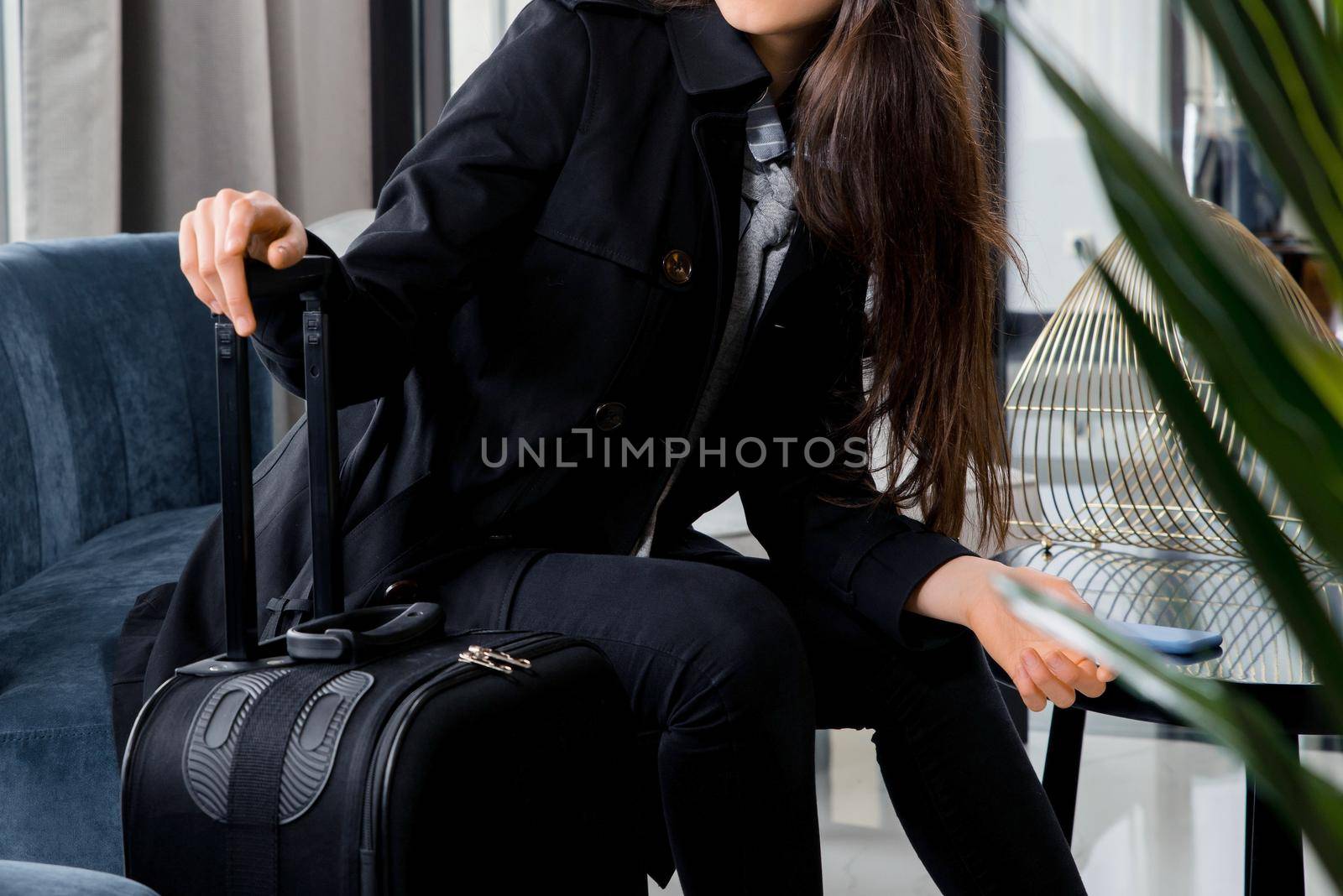 Woman with suitcases sitting in waiting area in airport business lounge