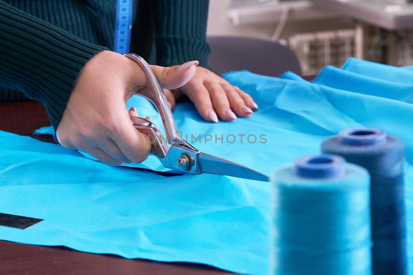 Dressmaker cutting fabric in atelier shop