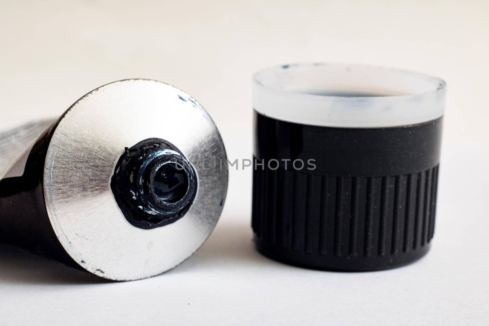 Open tube with blue paint on a white background close up