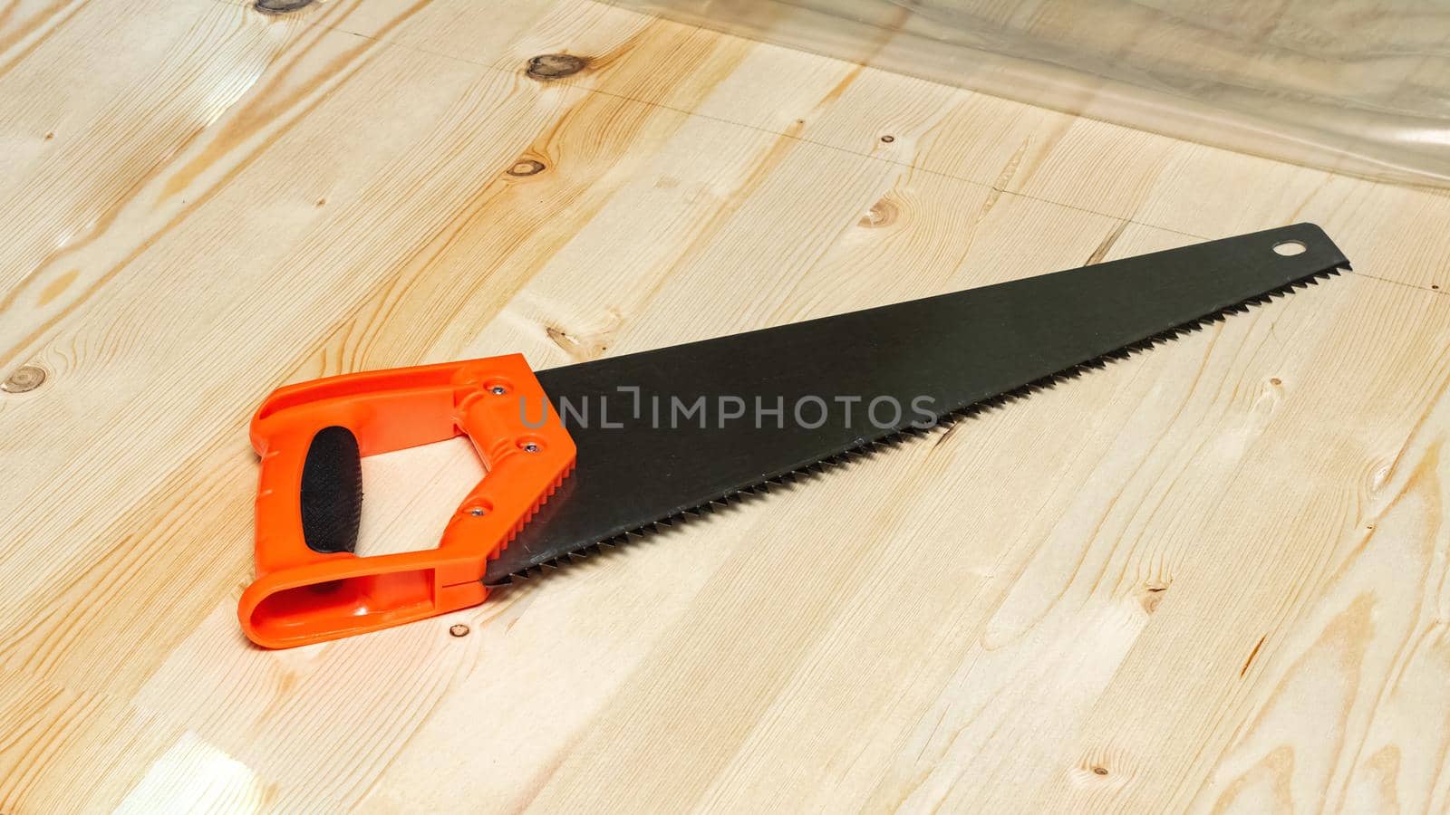 Saw with a plastic handle on a wooden board close up