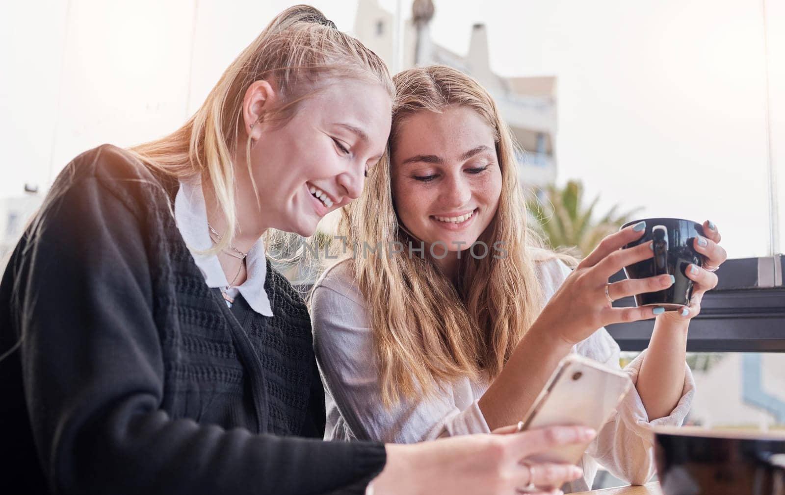Friends, coffee shop and smile at meme on phone, laugh at joke online and women networking in cafe. Smartphone, technology and communication on internet website, students with cellphone in restaurant.