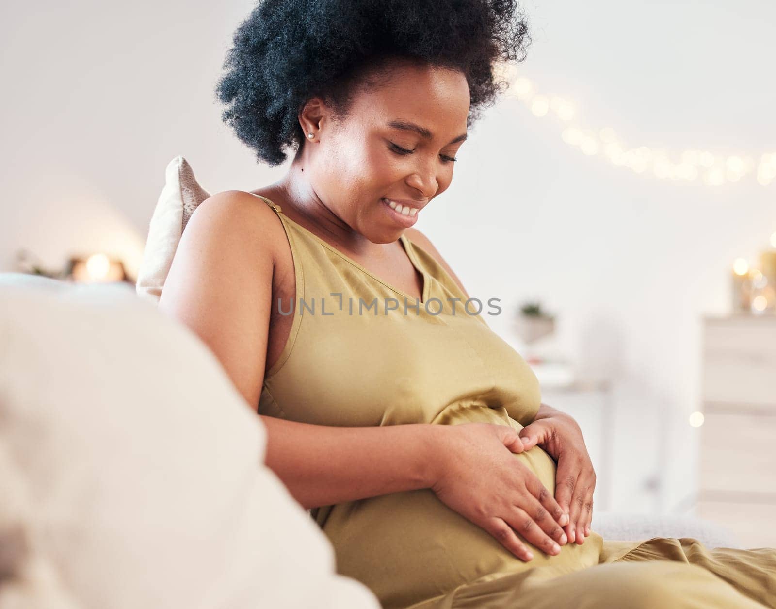 Pregnant stomach, heart hand sign and happy black woman feeling mother hope and love. Mom care, sofa and living room lounge with a person holding abdomen happy about pregnancy and baby in a house by YuriArcurs