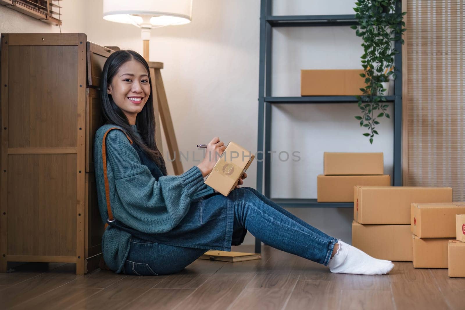 Happy young Asian woman entrepreneur, Smile for sales success after checking order from online shopping store in a laptop at home office, Concept of merchant business online and eCommerce..