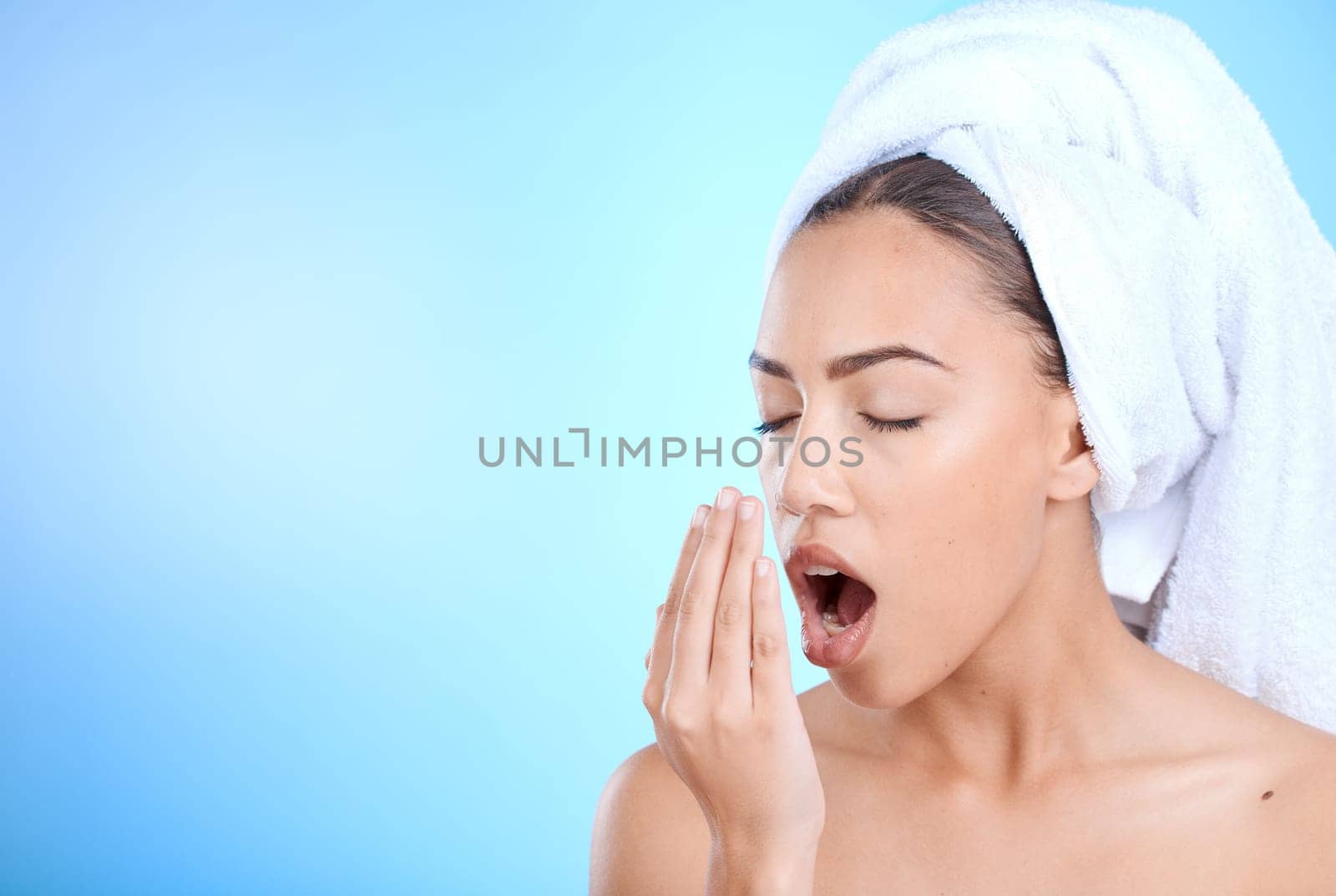 Shower, grooming and woman smelling breath for oral care isolated on blue background in a studio. Dental, healthcare and girl breathing into hand to check for odor problem on a mockup space backdrop.