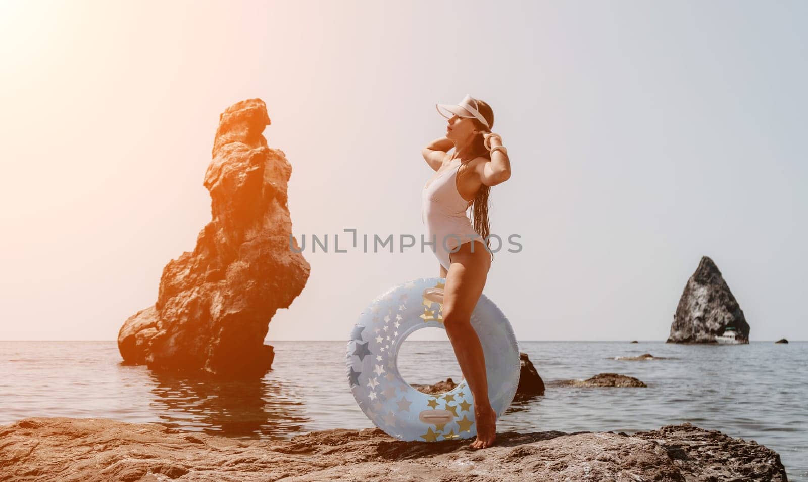 Woman summer sea. Happy woman swimming with inflatable donut on the beach in summer sunny day, surrounded by volcanic mountains. Summer vacation concept