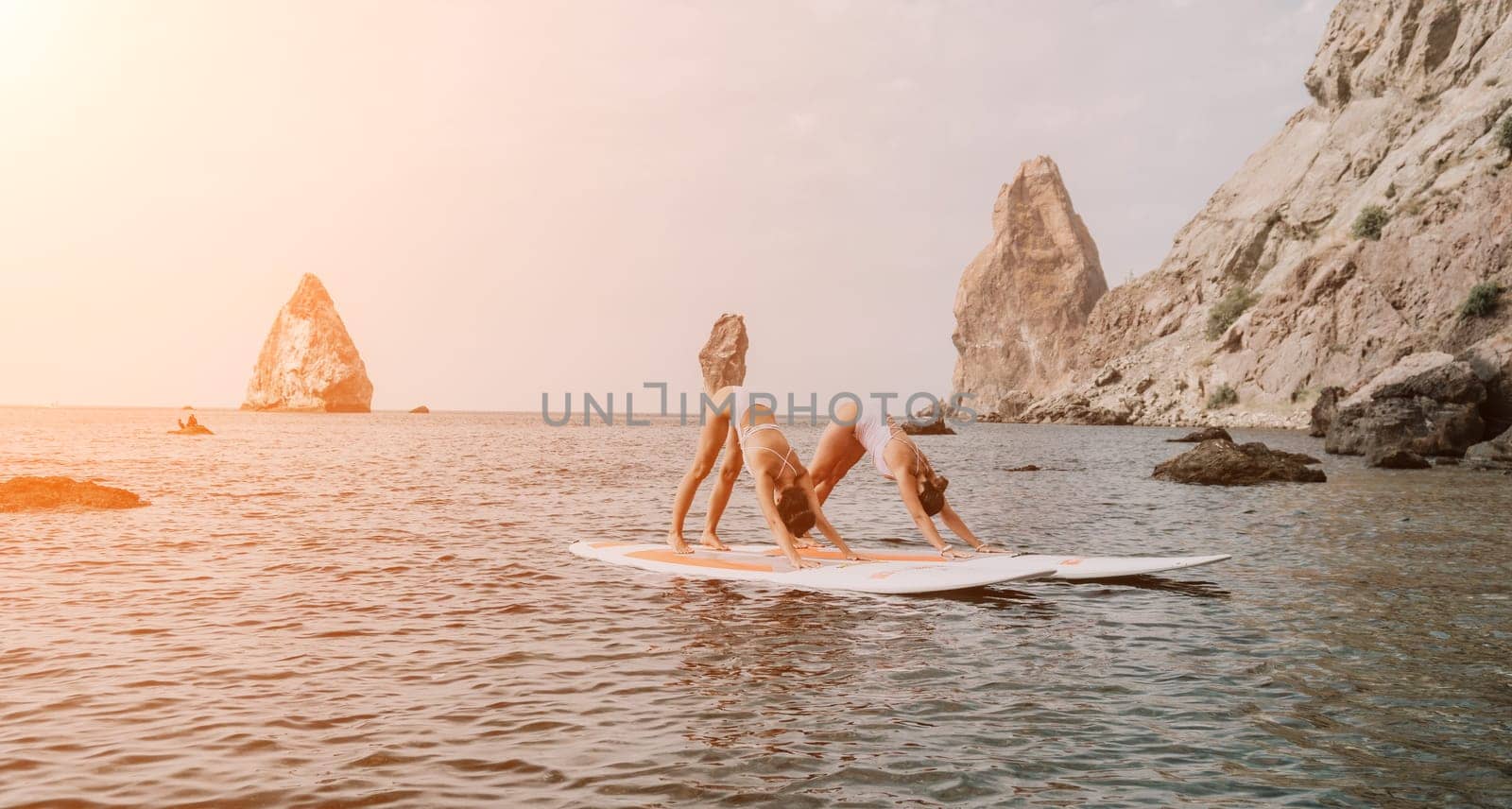 Woman sup yoga. Middle age sporty woman practising yoga pilates on paddle sup surfboard. Female stretching doing workout on sea water. Modern individual hipster outdoor summer sport activity