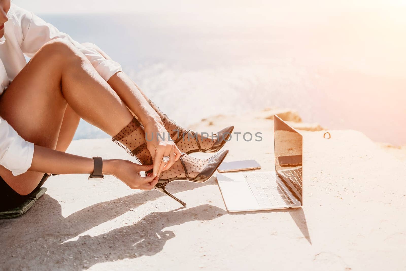 Woman sea laptop. Business woman in yellow hat freelancer with laptop working over blue sea beach. Girl relieves stress from work. Freelance, digital nomad, travel and holidays concept by panophotograph