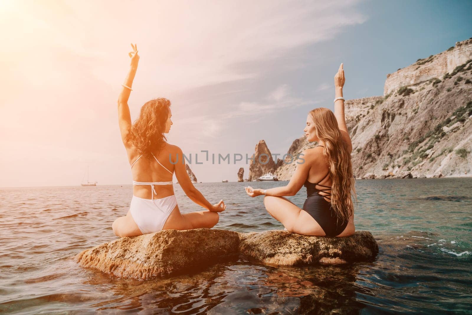 Woman sea yoga. Happy women meditating in yoga pose on the beach, ocean and rock mountains. Motivation and inspirational fit and exercising. Healthy lifestyle outdoors in nature, fitness concept. by panophotograph