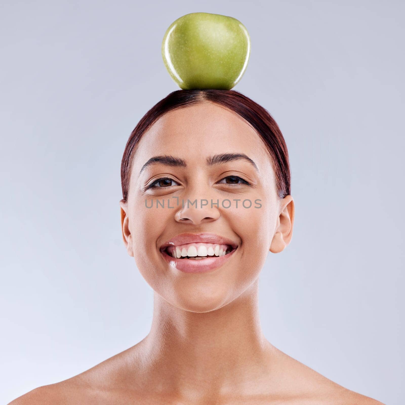 Apple, balance or portrait of happy woman in studio on white background for healthy nutrition or clean diet. Smile, face or beautiful girl with natural organic fruit on head for wellness benefits.