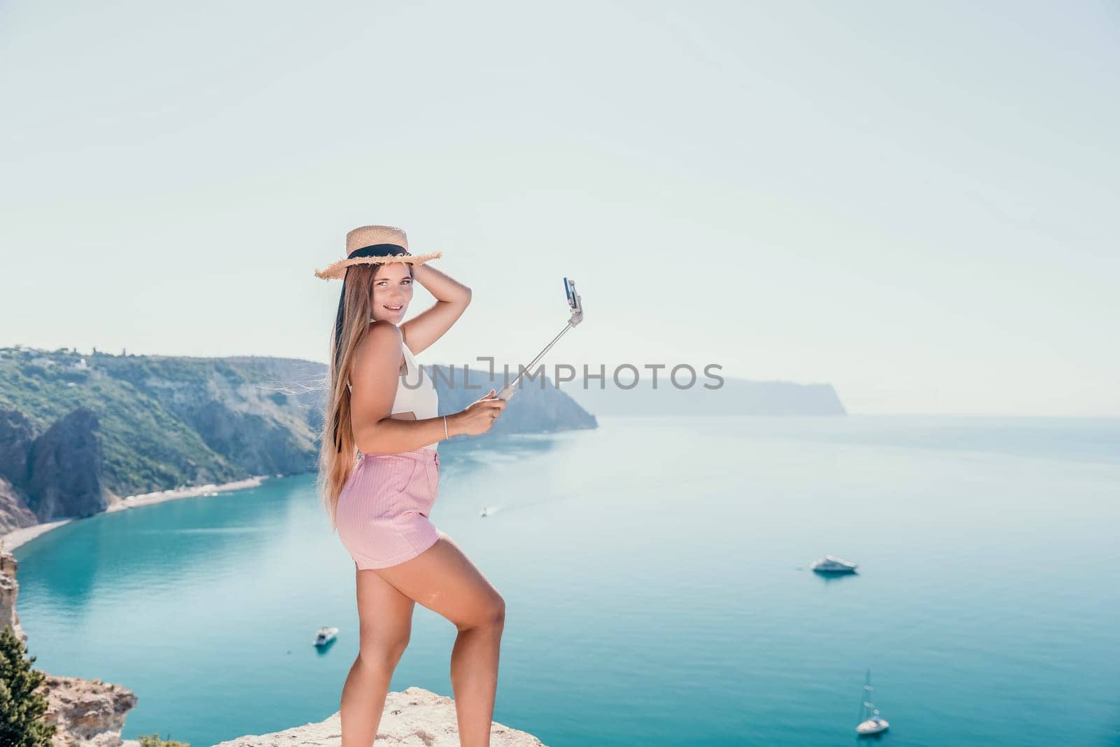 Woman sea laptop. Business woman in yellow hat freelancer with laptop working over blue sea beach. Girl relieves stress from work. Freelance, digital nomad, travel and holidays concept by panophotograph