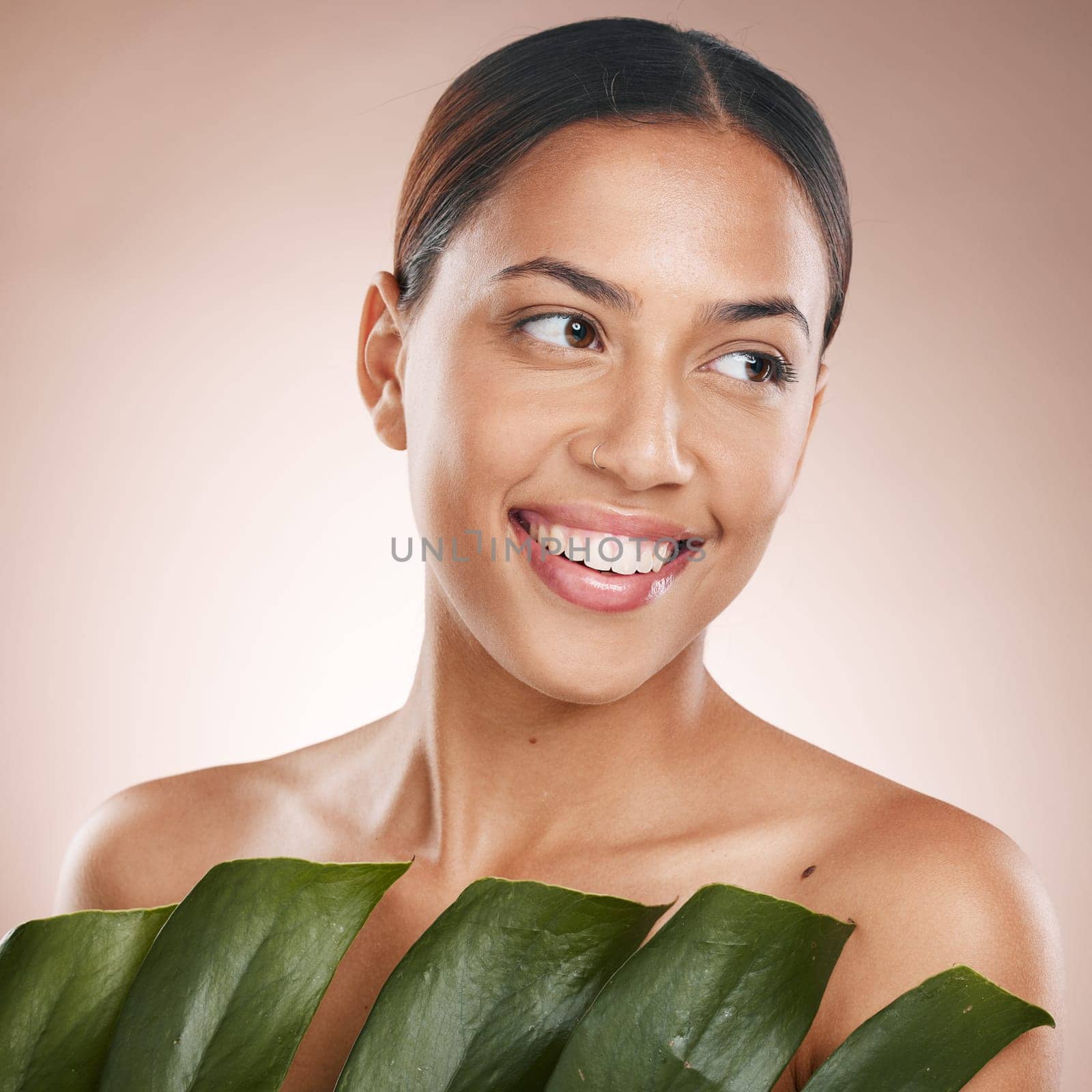 Woman, face skincare and monstera leaf on pink studio background for organic dermatology, self love or healthcare wellness. Happy, smile or beauty model with green plant, natural makeup or cosmetics.