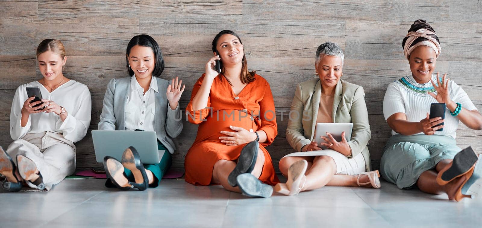 Teamwork, technology and diversity with a business team sitting on the floor in their office for work. Collaboration, communication and corporate design with a woman employee group working together.