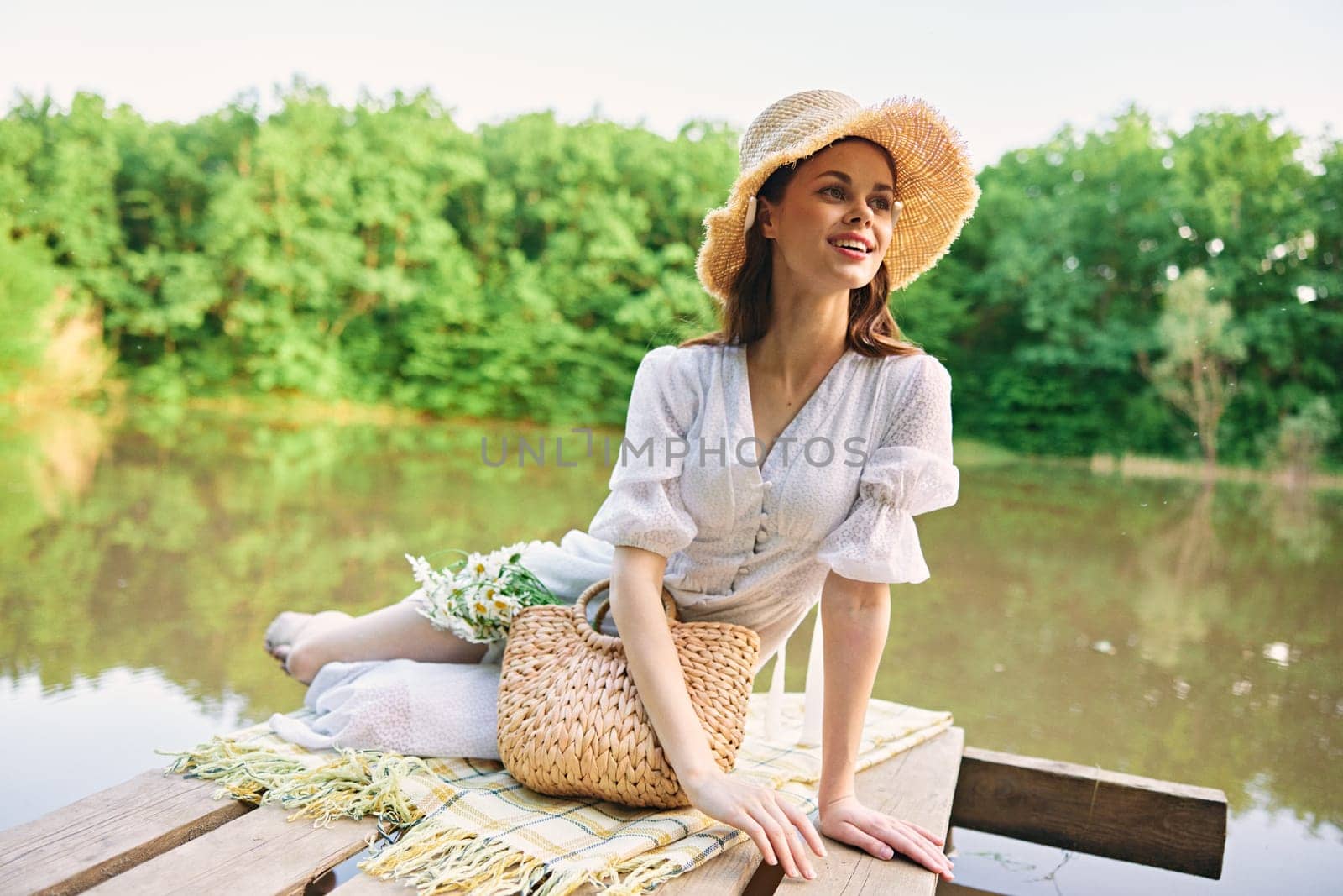 happy woman in a wicker hat resting in nature by the lake in summer. High quality photo