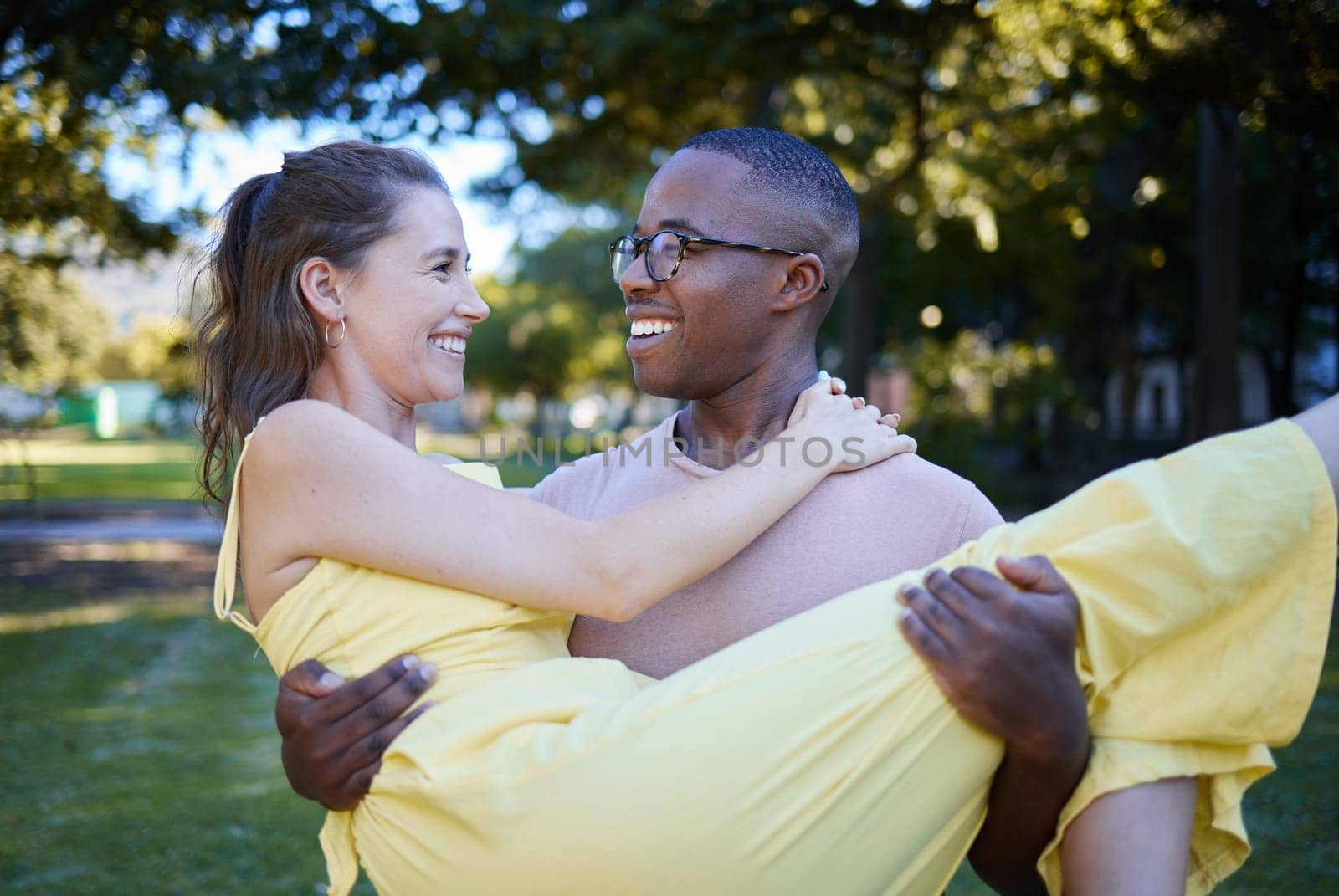 Love, park and carrying with an interracial couple bonding outdoor together on a romantic date in nature. Summer, romance and diversity with a man and woman dating outside in a green garden.