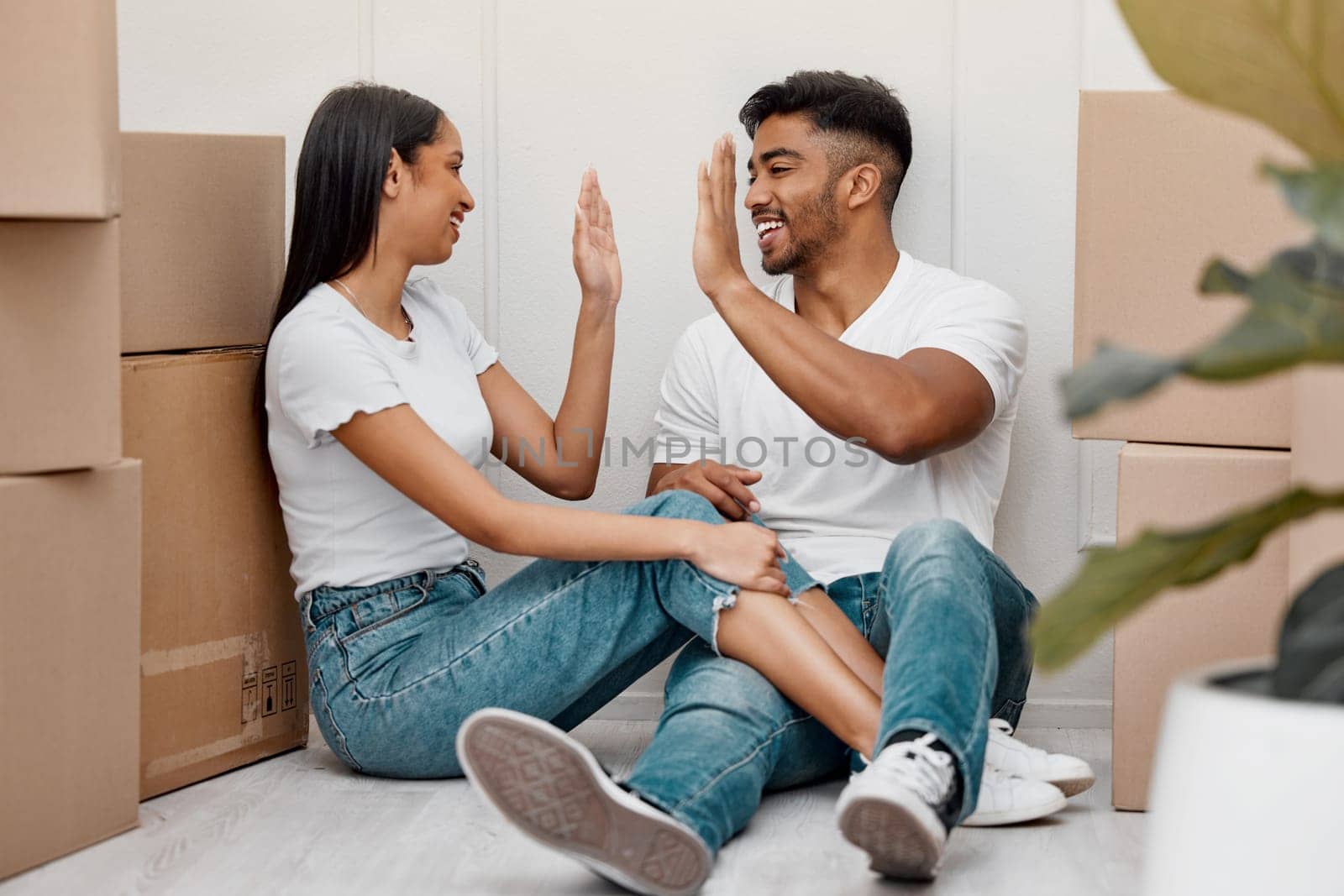 Box, celebration and couple high five in new home excited for property, apartment and real estate investment, Relationship, house and man and woman celebrate with smile, boxes and happy on moving day.