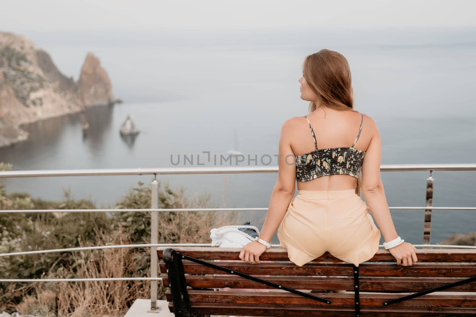 Woman travel sea. Happy tourist taking picture outdoors for memories. Woman traveler looks at the edge of the cliff on the sea bay of mountains, sharing travel adventure journey.