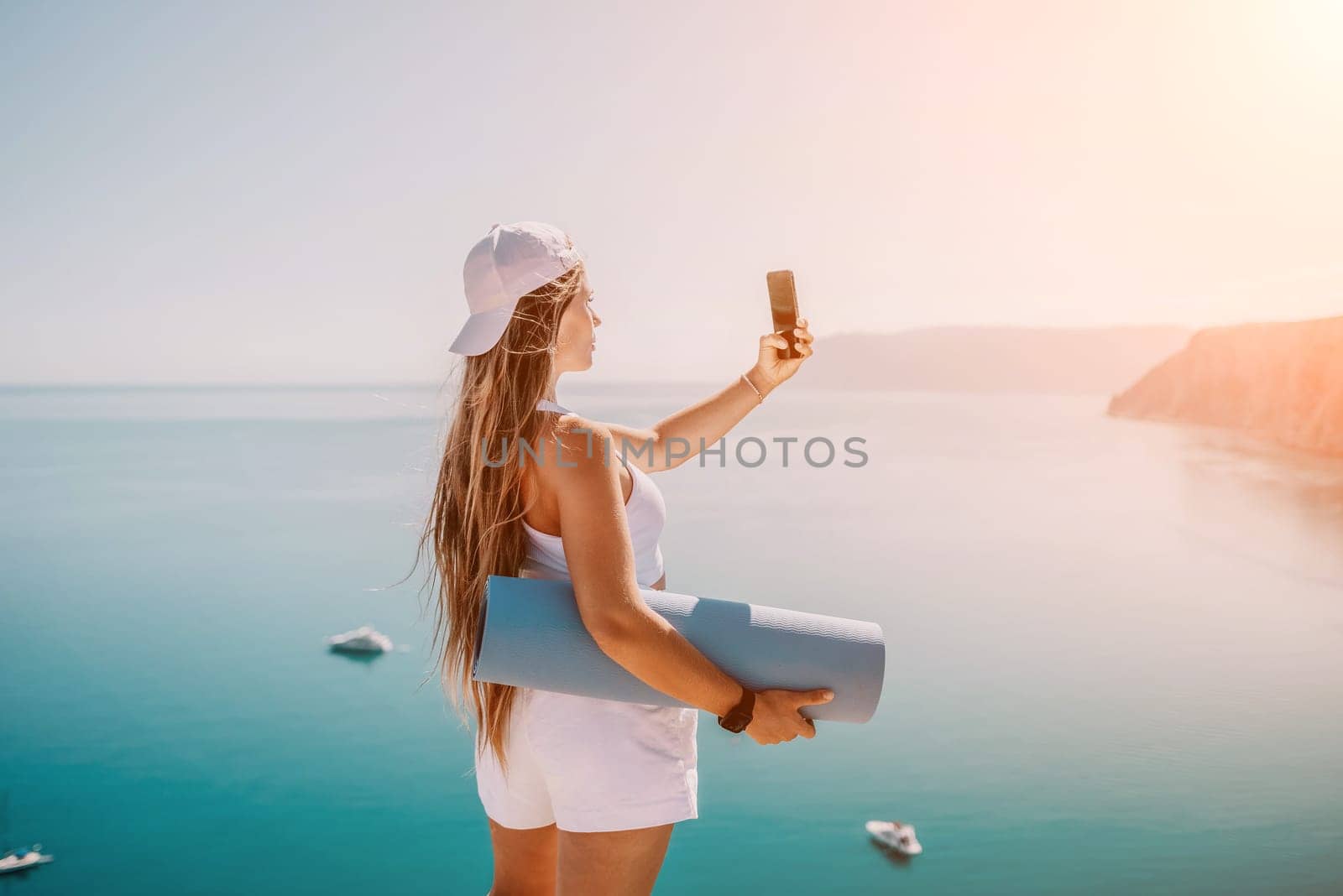 Young woman with black hair, fitness instructor in pink sports leggings and tops, doing pilates on yoga mat with magic pilates ring by the sea on the beach. Female fitness daily yoga concept