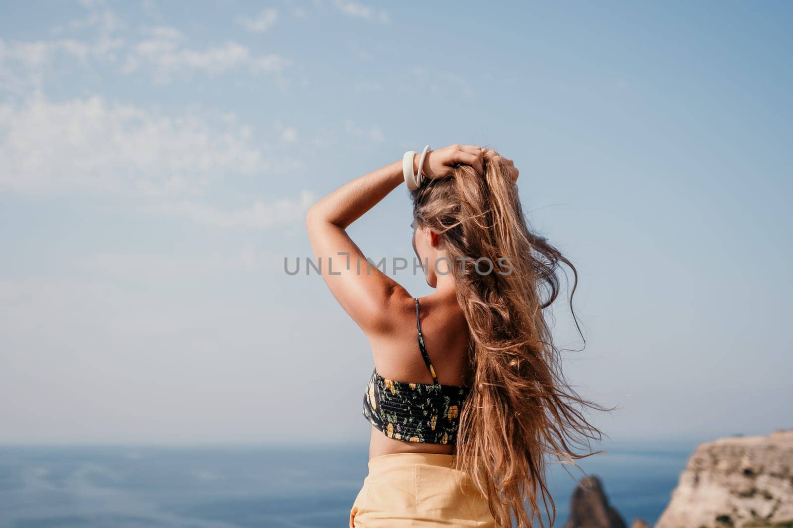 Woman travel sea. Happy tourist taking picture outdoors for memories. Woman traveler looks at the edge of the cliff on the sea bay of mountains, sharing travel adventure journey.