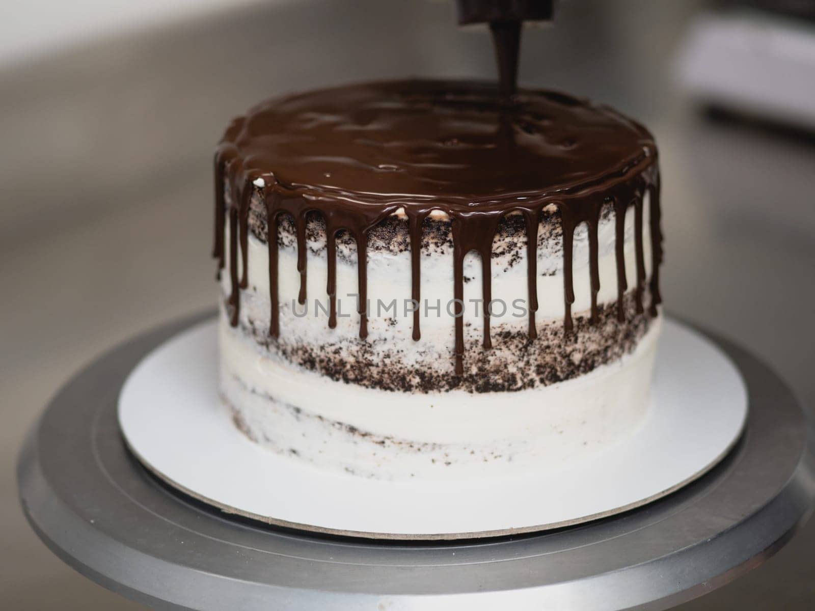 pastry chef preparing a chocolate frosted dripped icing cup cake with sweet fruit topping and golden brush strokes