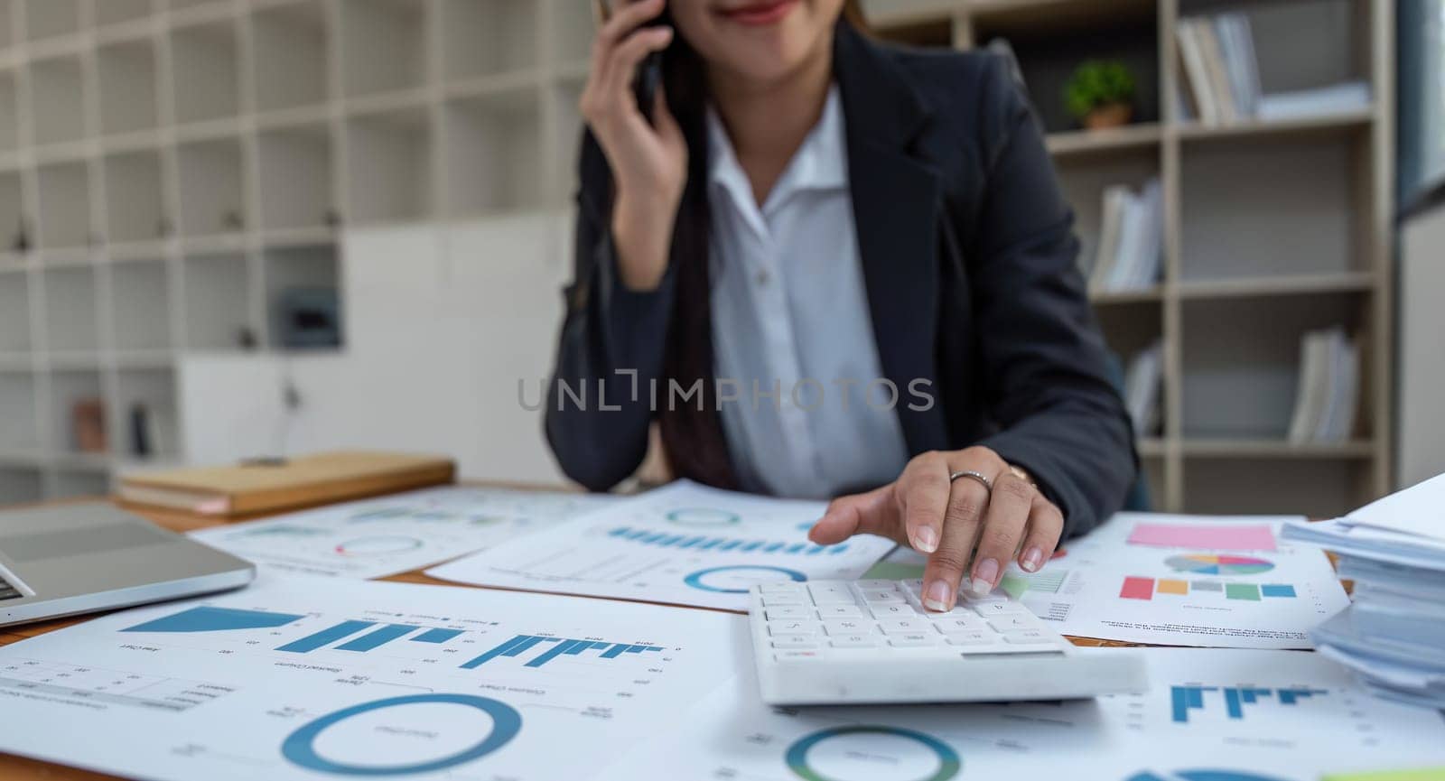 Close-up of businesswoman hands using a calculator to check company finances and earnings and budget. Business woman calculating monthly expenses, managing budget, papers.