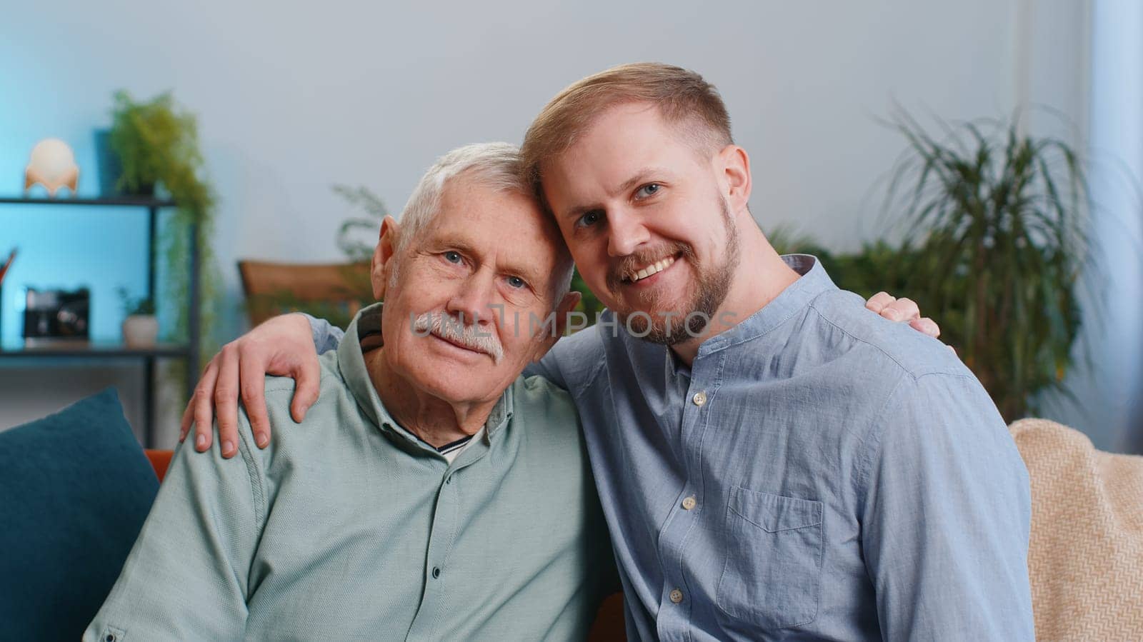 Portrait of mature grandfather with young adult man grandson smiling happy embracing hugging at home by efuror