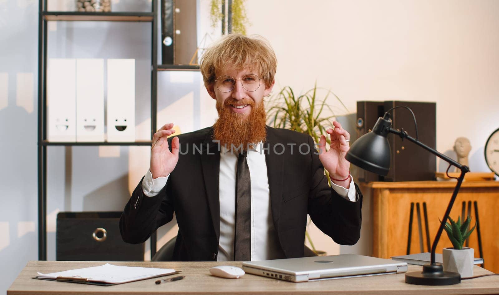 Young businessman working on laptop computer, meditating, doing yoga breathing exercise in lotus position at home office. Calm serene freelancer man taking break. Busy occupation. Peace of mind