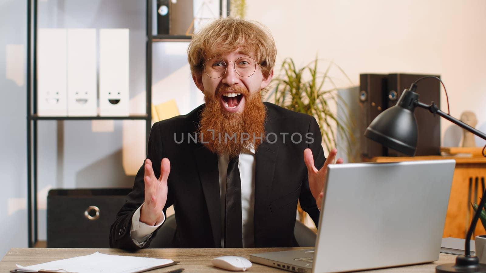 Oh my God, Wow. Happy amazed young bearded businessman working on laptop shocked by sudden victory, game winning, lottery goal achievemen, good news. Manager man freelancer at home office workplace