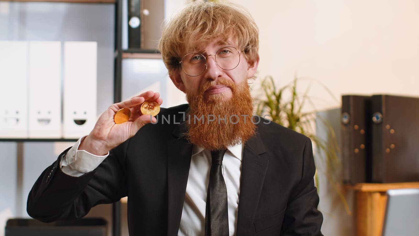 Young bearded businessman stock trader earning bitcoins after online monitoring trading operations. Increasing wealth, financial prosperity. Freelancer man working on laptop at home office workplace