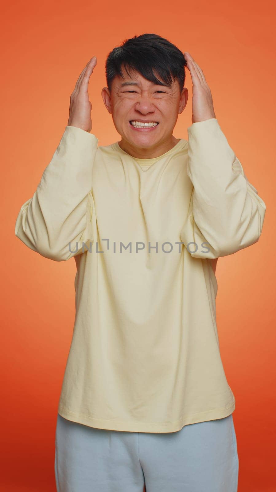 Handsome asian man feeling hopelessness loneliness, nervous breakdown, loses becoming surprised by lottery results, bad fortune, loss, unlucky news. Guy isolated on orange background. Vertical