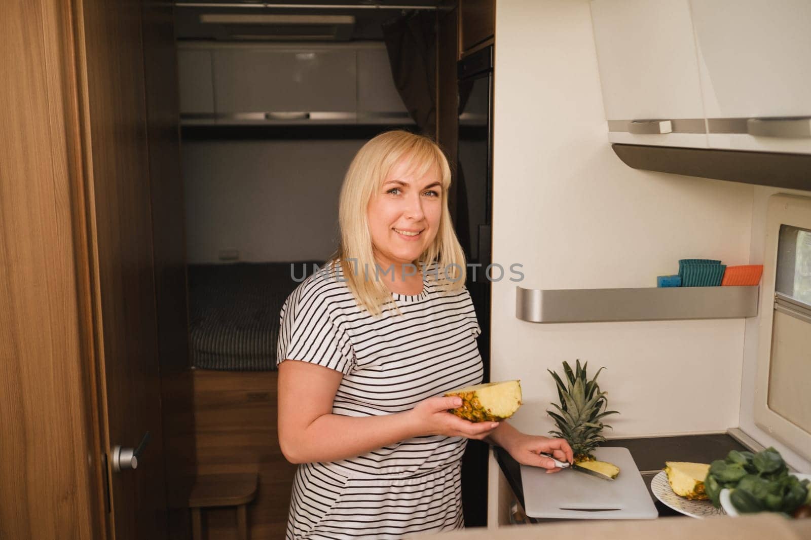 a woman cooking food in the kitchen inside a motorhome, the interior of a motorhome.