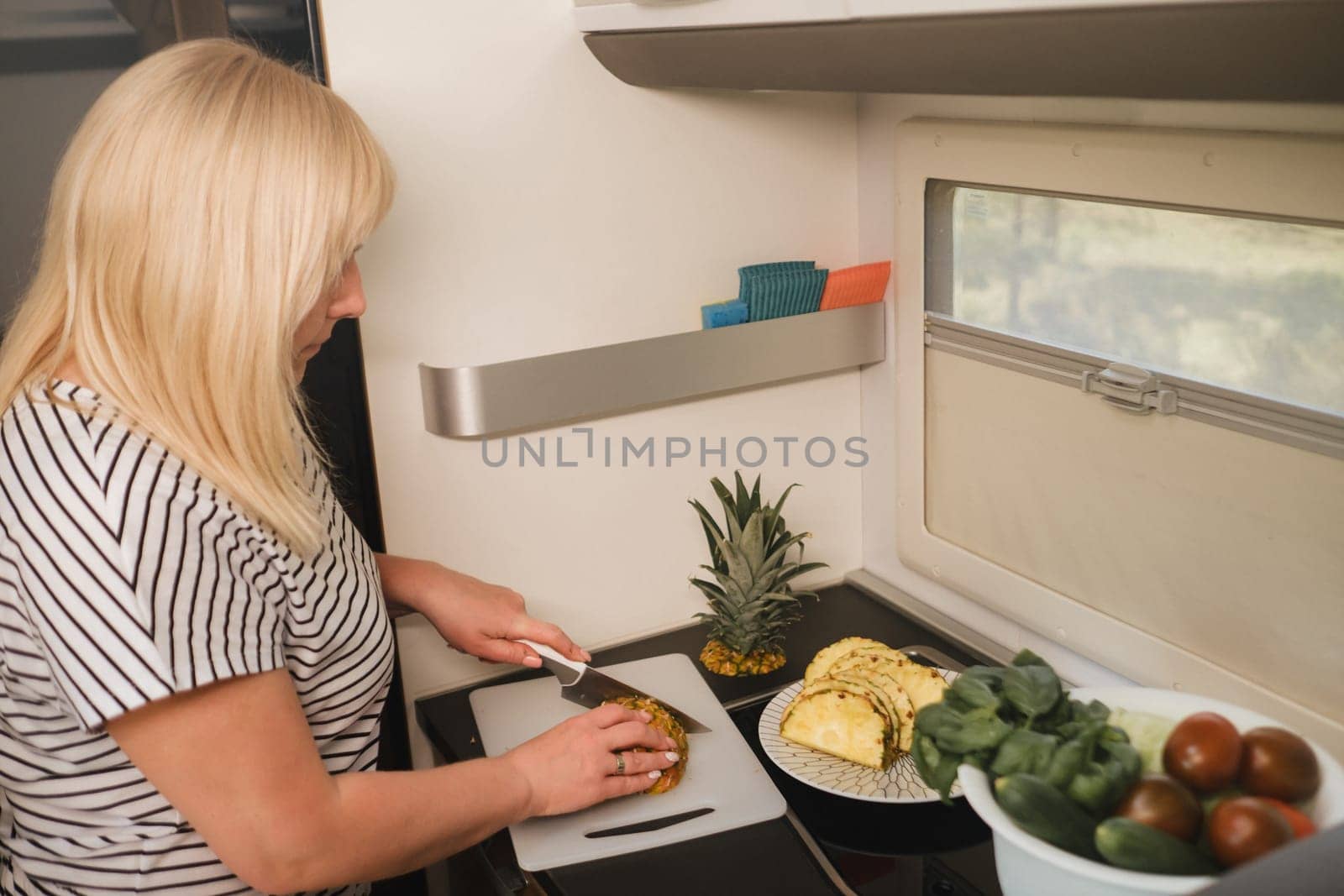 a woman cooking food in the kitchen inside a motorhome, the interior of a motorhome.