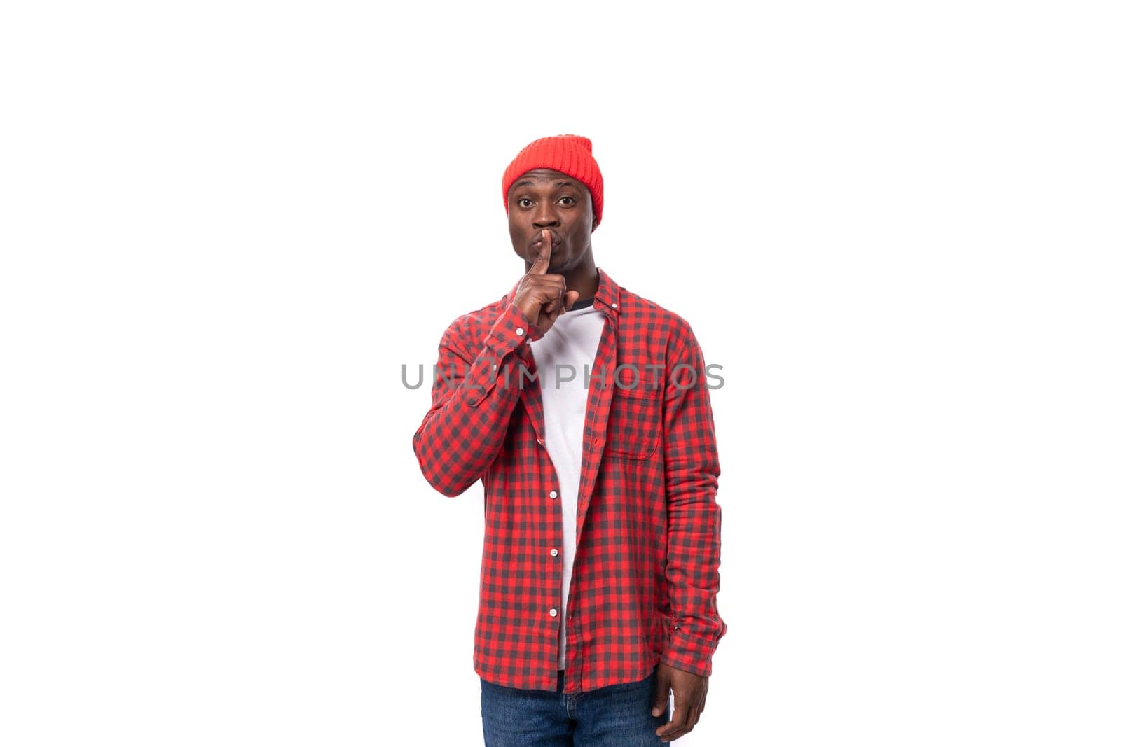 handsome joyful dark-skinned man in a casual plaid shirt keeps a secret on a white background with copy space by TRMK