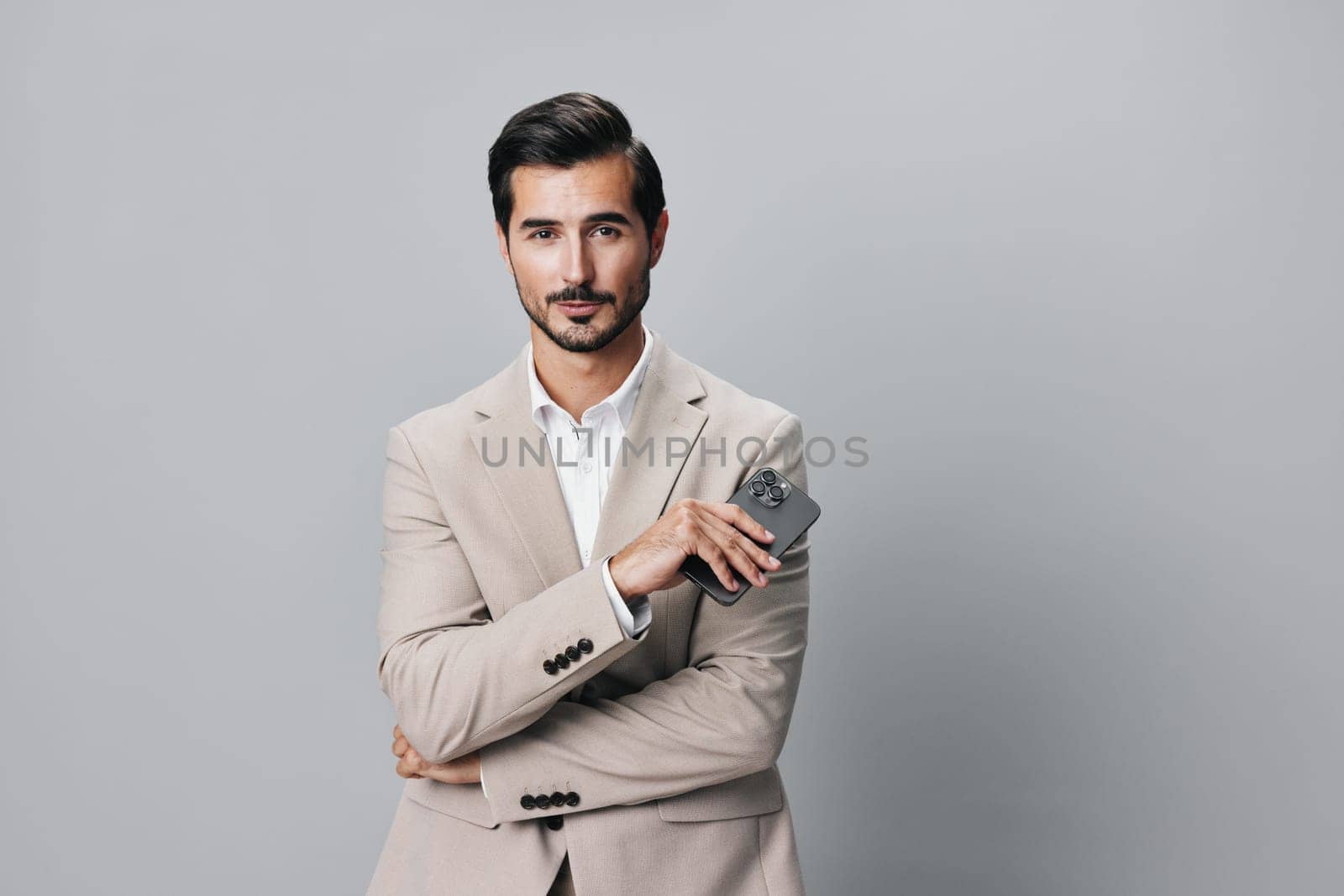 man internet lifestyle smile phone beige business suit happy hold communication corporate cyberspace portrait holding message studio smartphone application call mobile