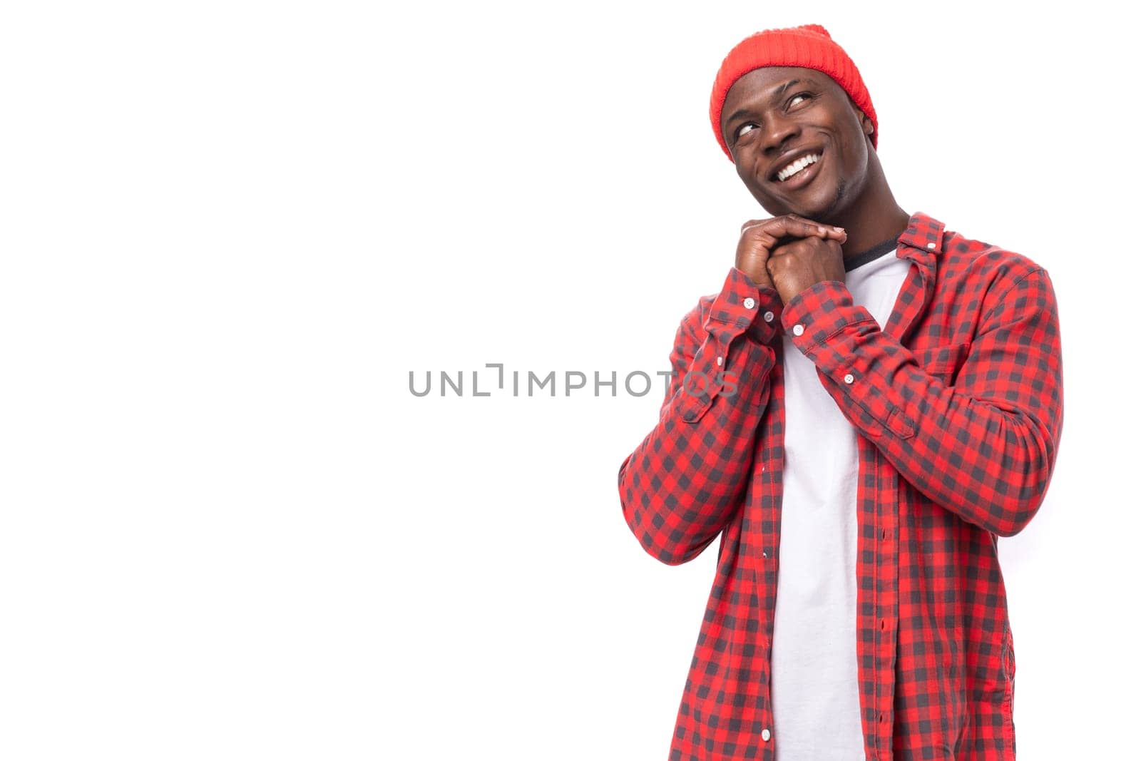 handsome young ethnic african guy in red plaid shirt reports dreaming over isolated white background.