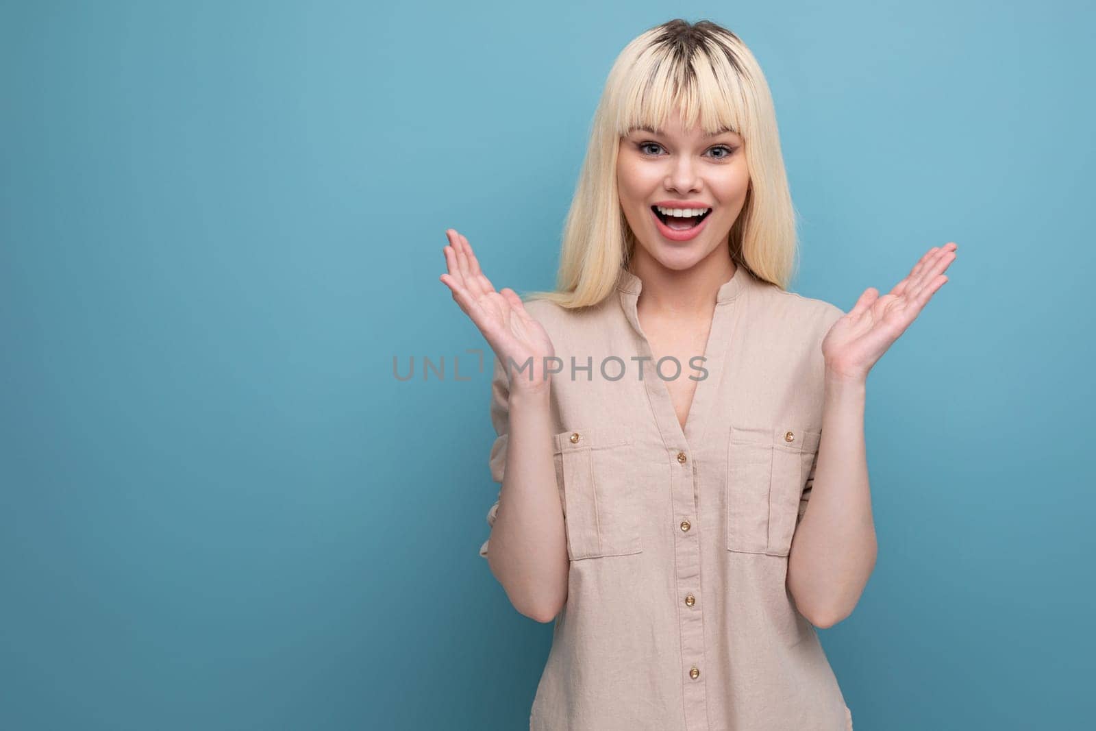 joyful surprised blond young woman spreads her arms to the sides.