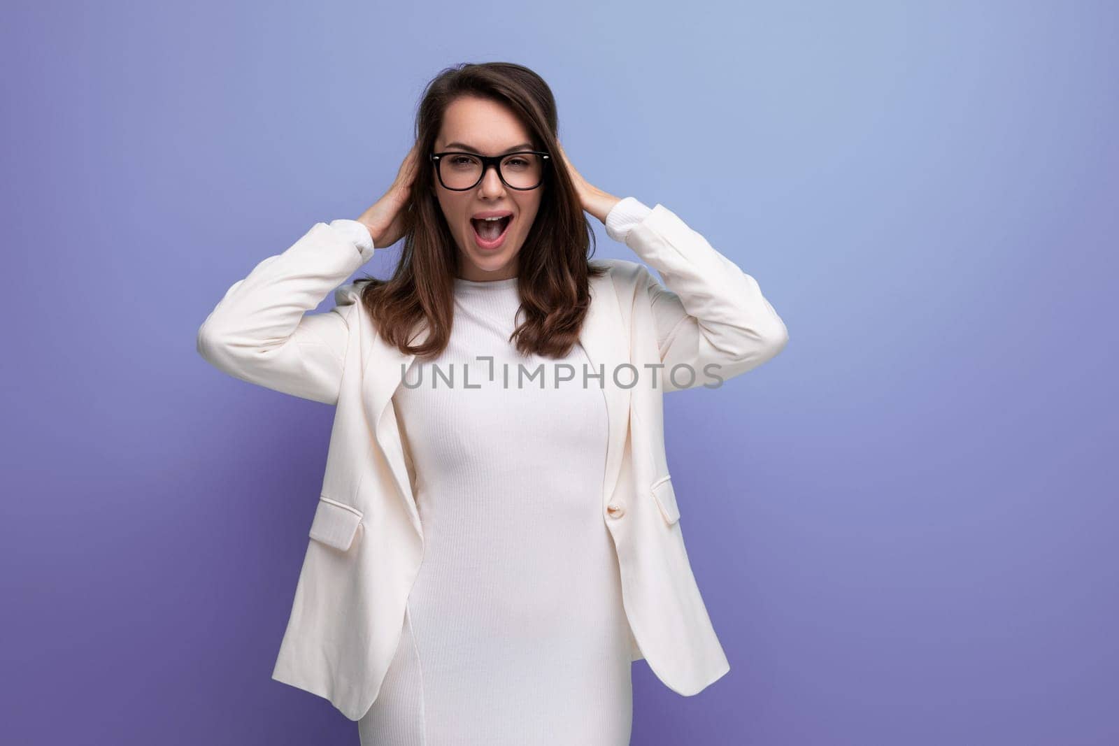 smart woman with thick dark hair in white outfit on studio background.