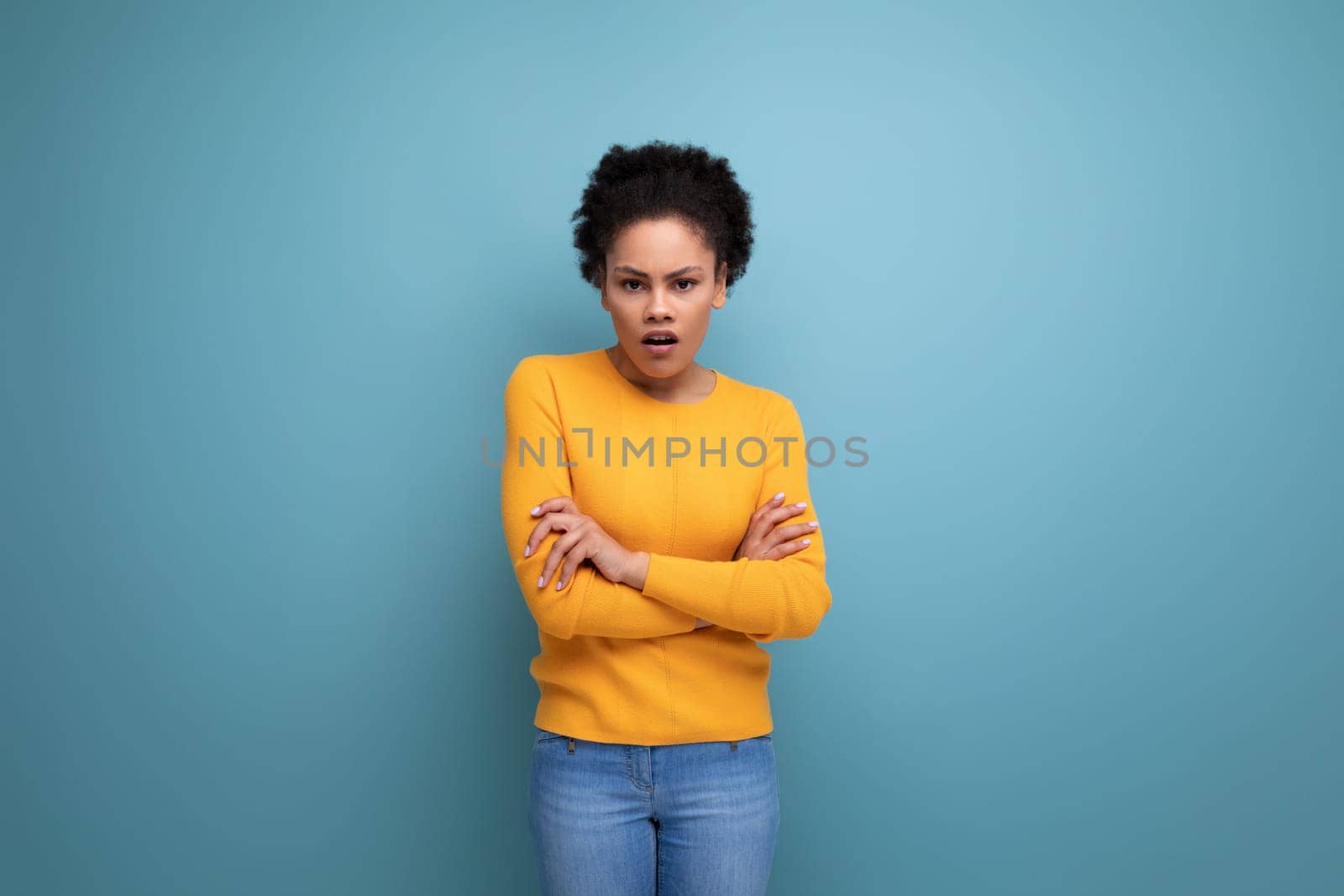 pretty young latin woman with afro hair posing on studio background.