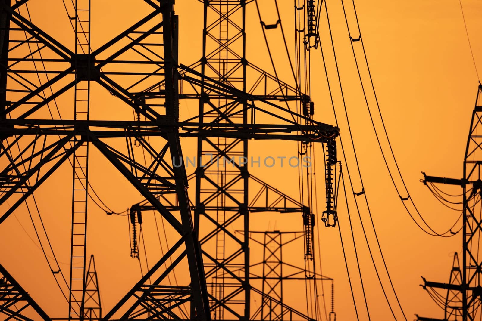 High voltage electric transmission tower. High voltage power lines on electric pylon against a sunset sky. Electrical infrastructure. Energy crisis. Electric power distribution. Energy distribution. by Fahroni