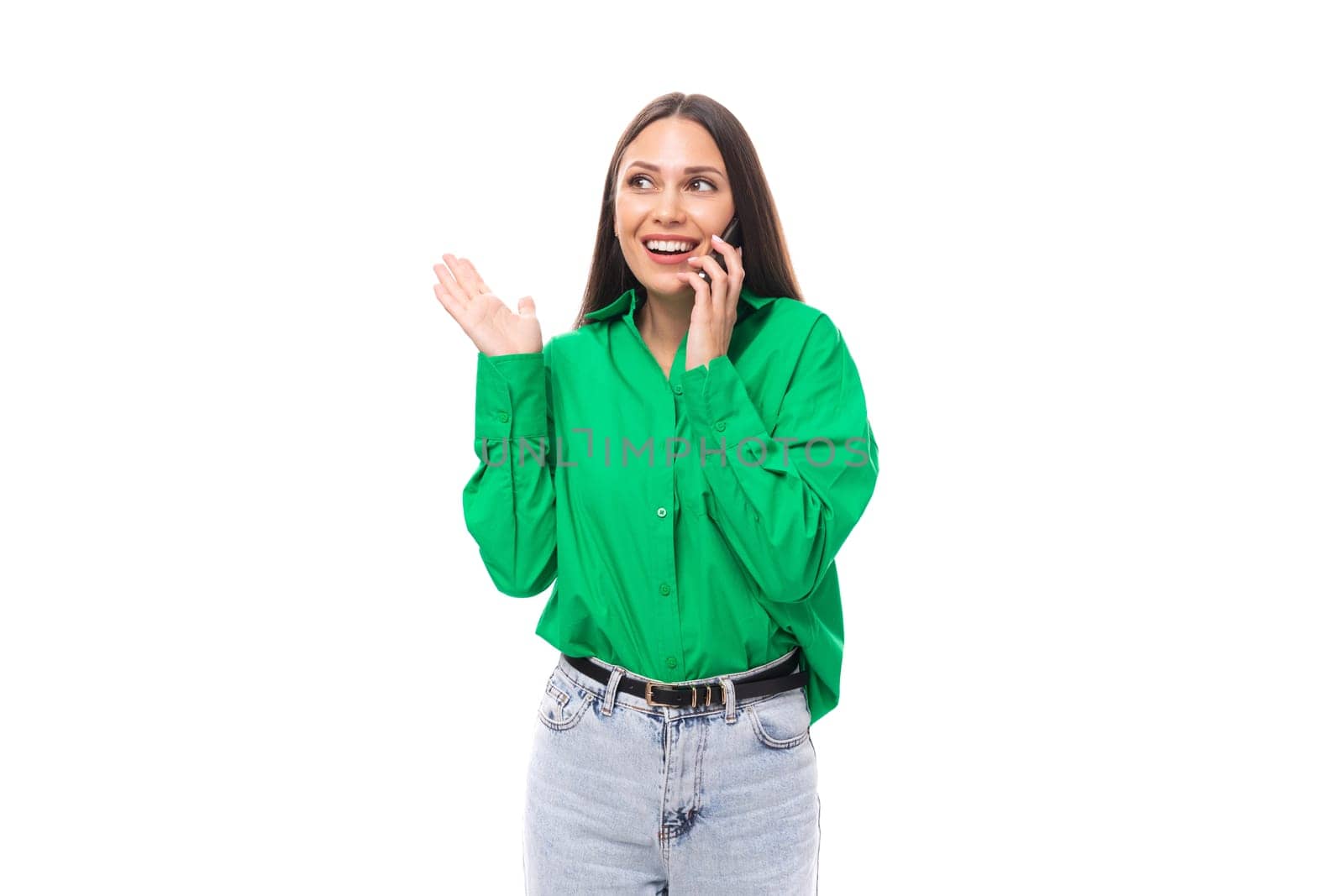 portrait of a smart pensive slim cute brown-eyed brunette woman dressed in a green shirt chatting on the phone on a white background with copy space.