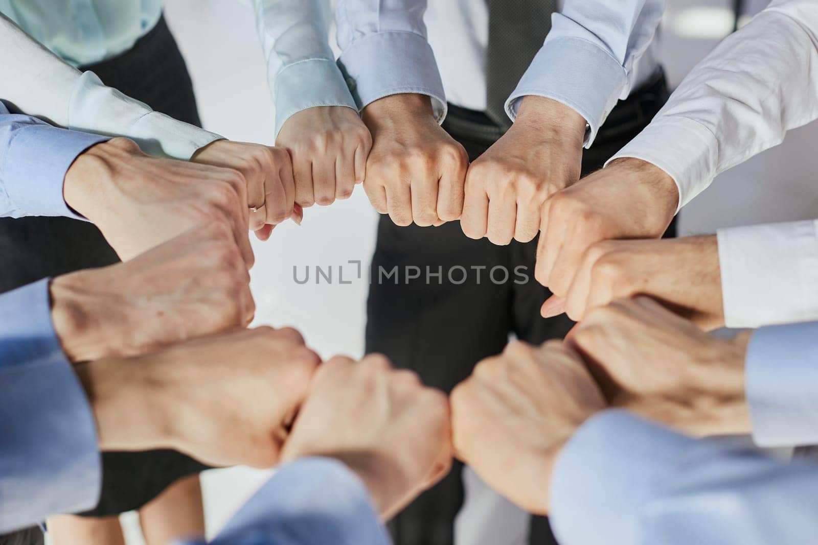 Closeup view businesspeople standing in circle fists bumping showing unity